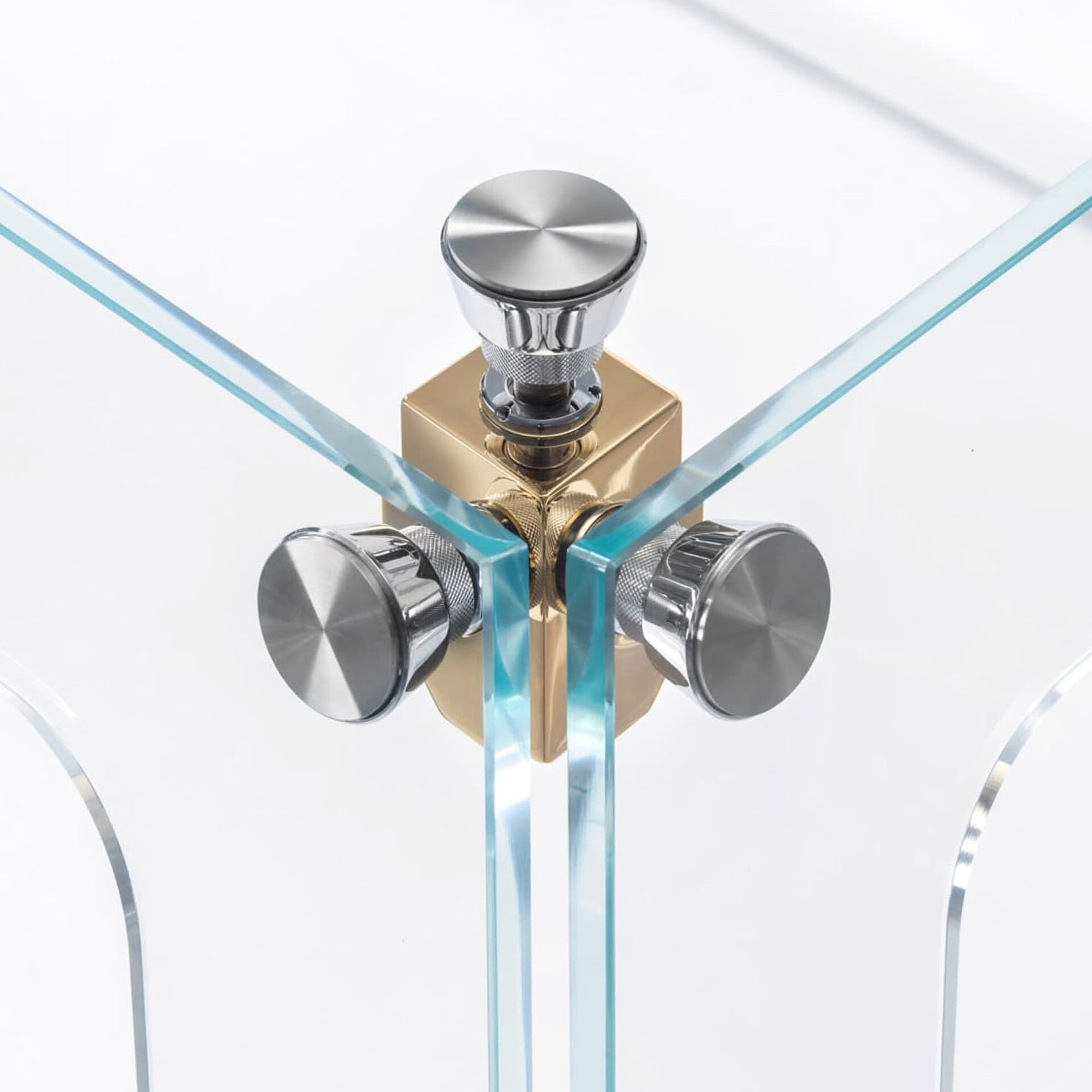 Sleek glass corner table with modern chrome and brass hardware, stylish and functional furniture piece.