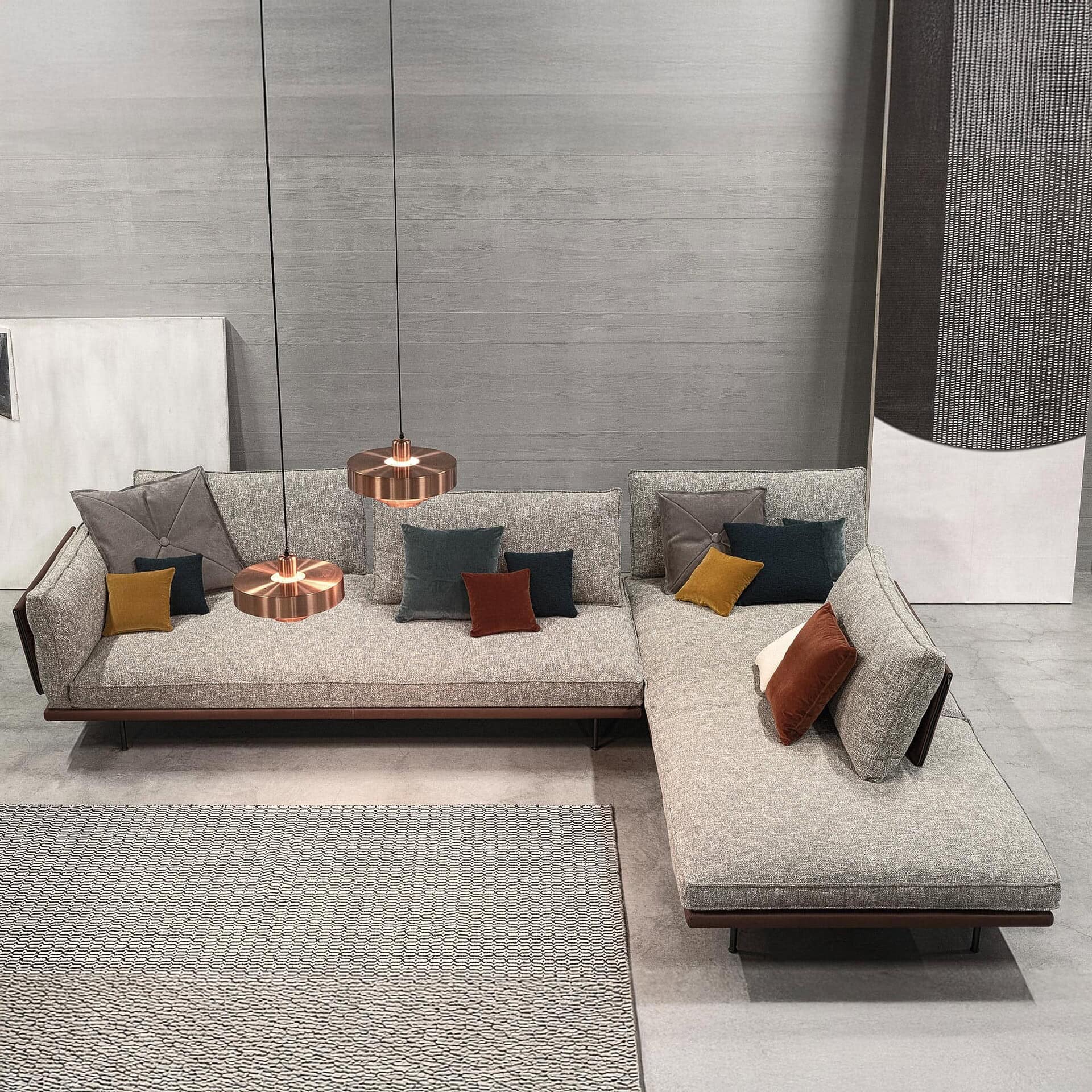 Divine Modular Sectional Sofa in gray fabric with extended chaise configuration, styled with bold throw pillows and overhead pendant lights.