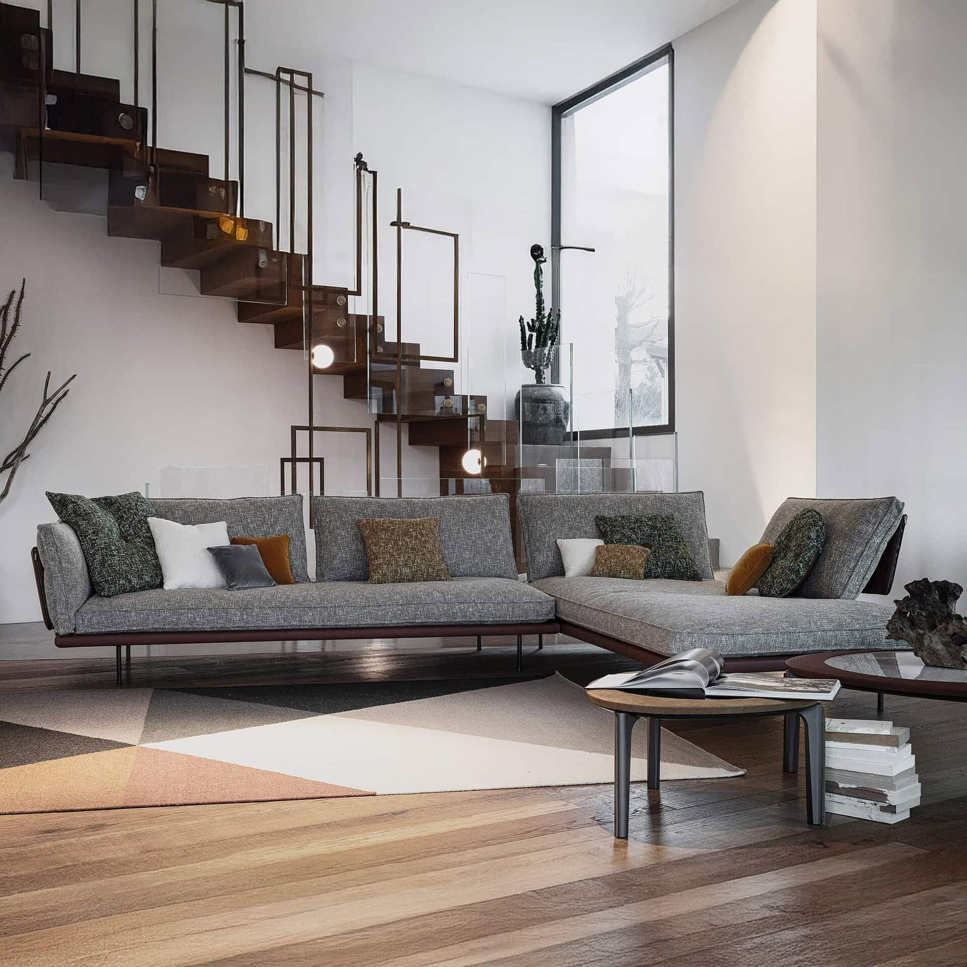 Divine Modular Sectional Sofa in gray fabric with chaise, styled in a bright modern space with wood staircase and floor-to-ceiling windows.
