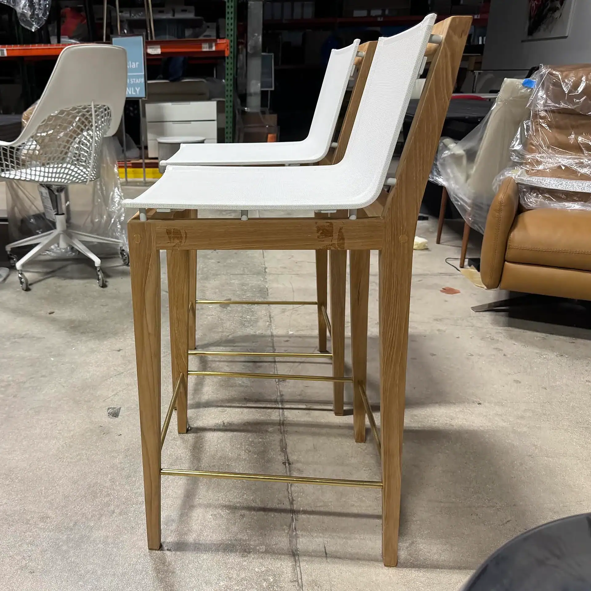 Harbour Byron outdoor bar stools with white seats and wooden legs in a store.