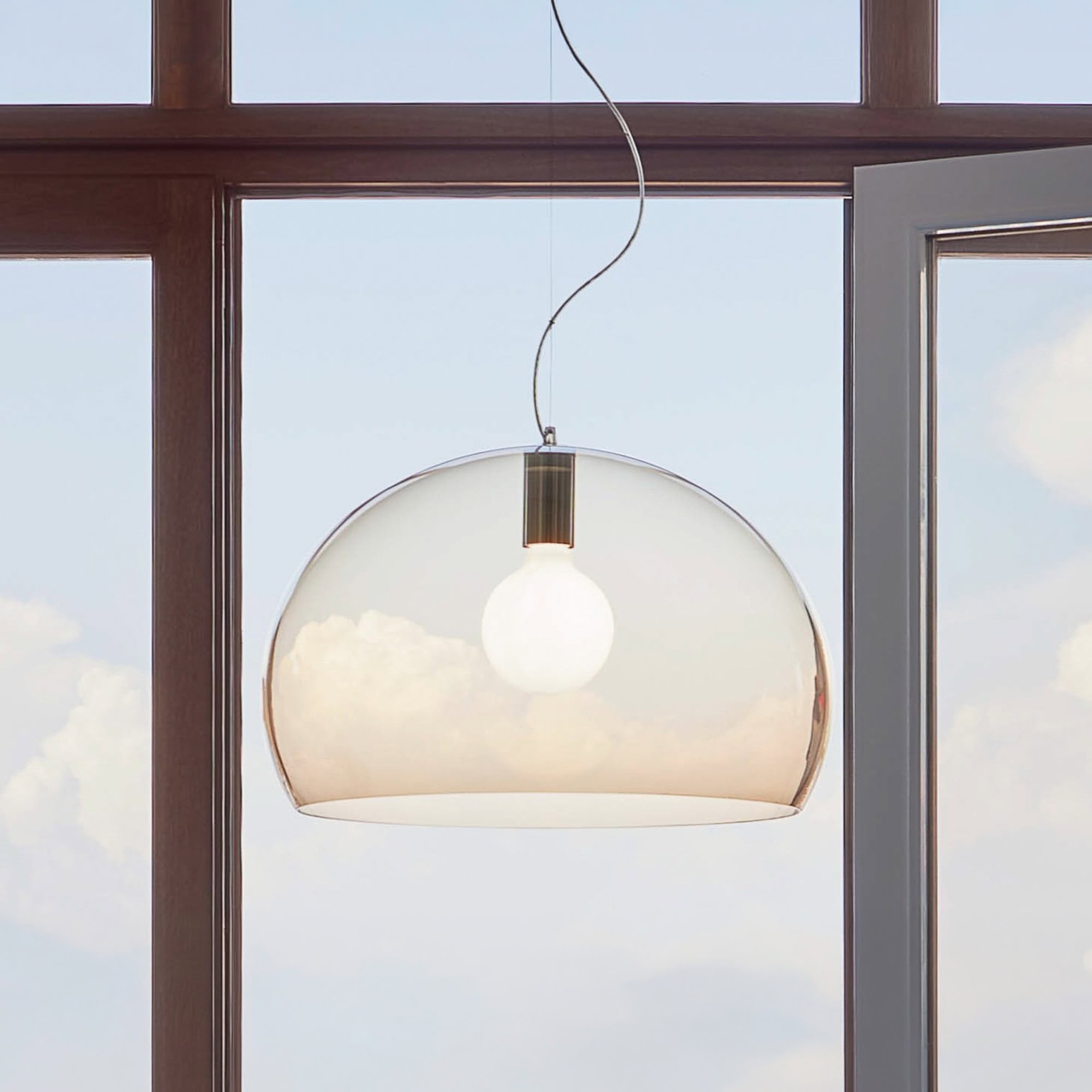 Pendant light fixture with a sleek, contemporary design, hanging in a well-lit room with large windo.