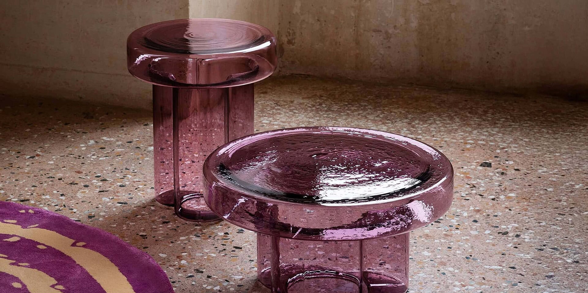 Translucent pink glass accent tables with circular tops and cylindrical bases.