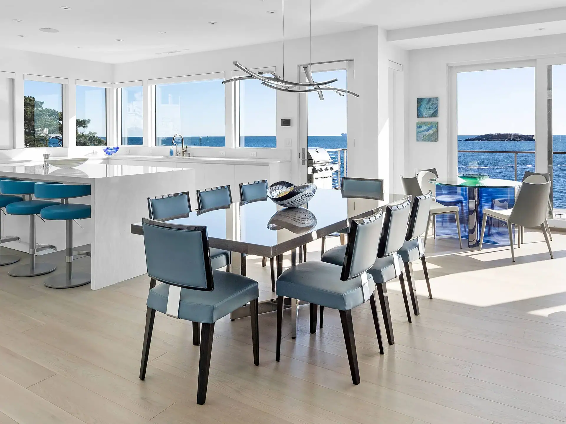 Elegant coastal dining room with ocean views, featuring contemporary furniture and large windows.