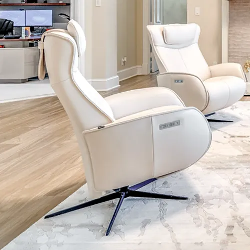 Two cream-colored leather recliners with black bases on a light rug in a modern room.