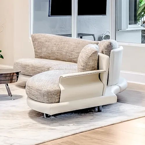 A modern L-shaped sofa with light beige frame and grey fabric cushions on a rug in a living room.