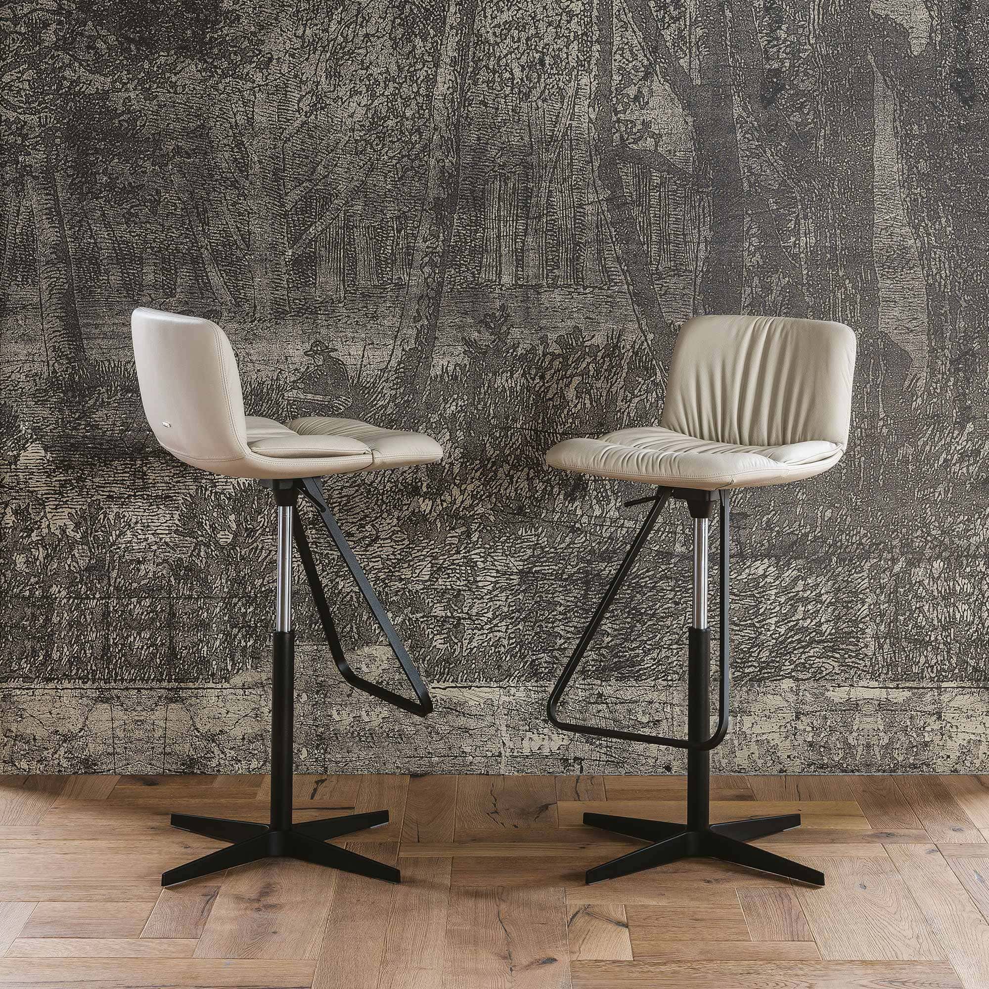 Two Axel X Stools with upholstered seats and metal swivel bases shown in a modern interior setting.