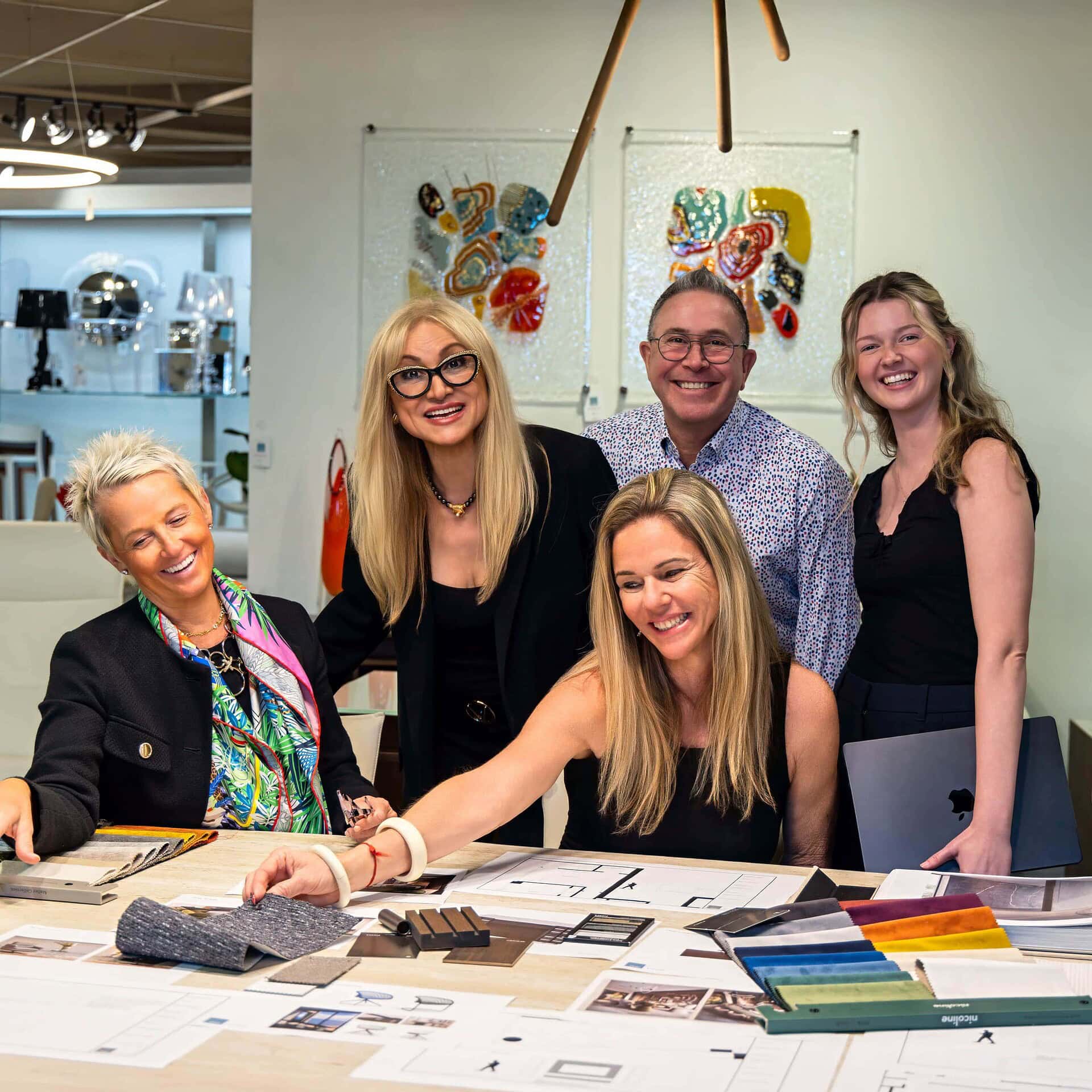 Vibrant team of interior designers collaborating on furniture and decor choices at Sklar Furnishings showroom.