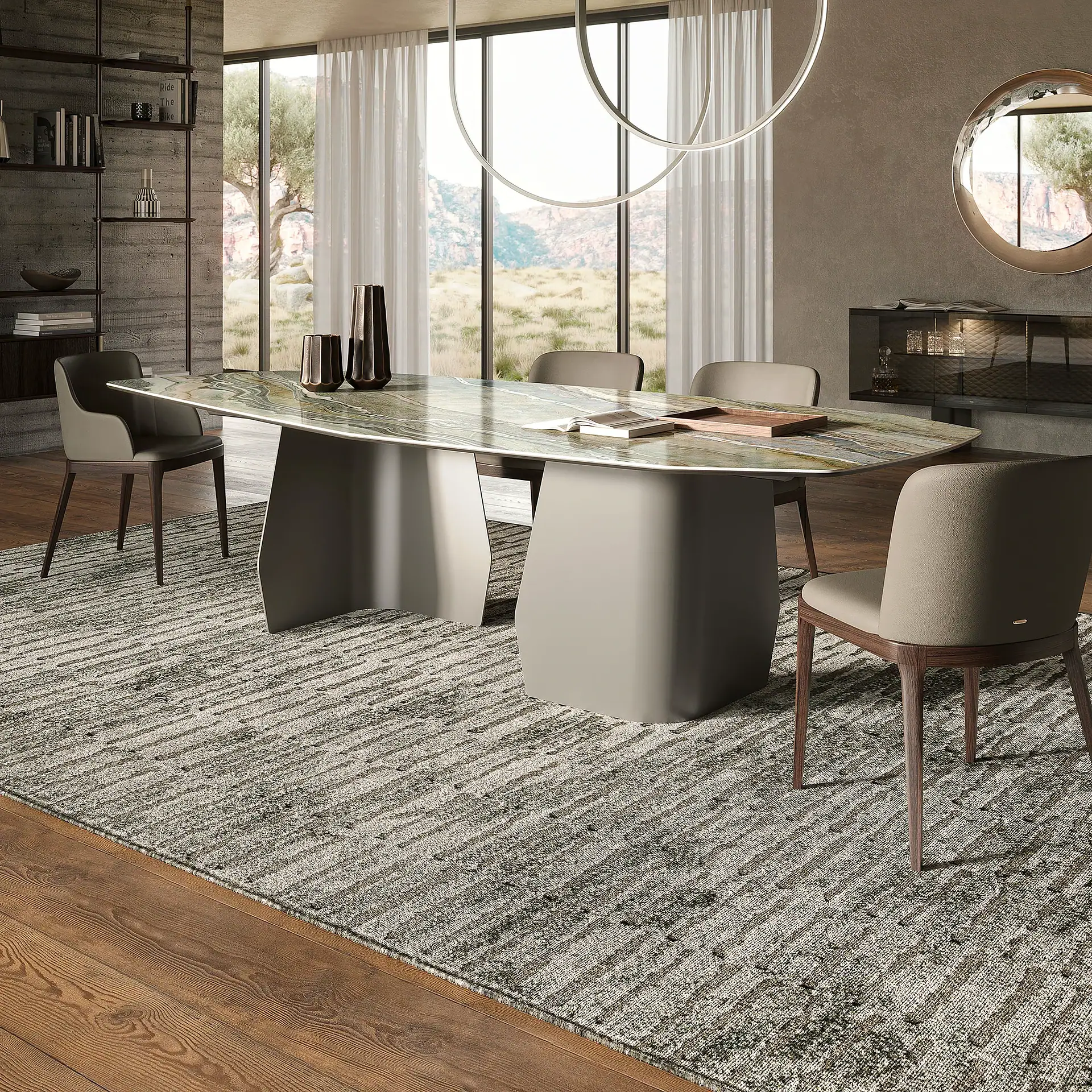 A modern dining room with a large marble-topped table, taupe leather chairs, a striped rug, and a large window overlooking a mountainous landscape.