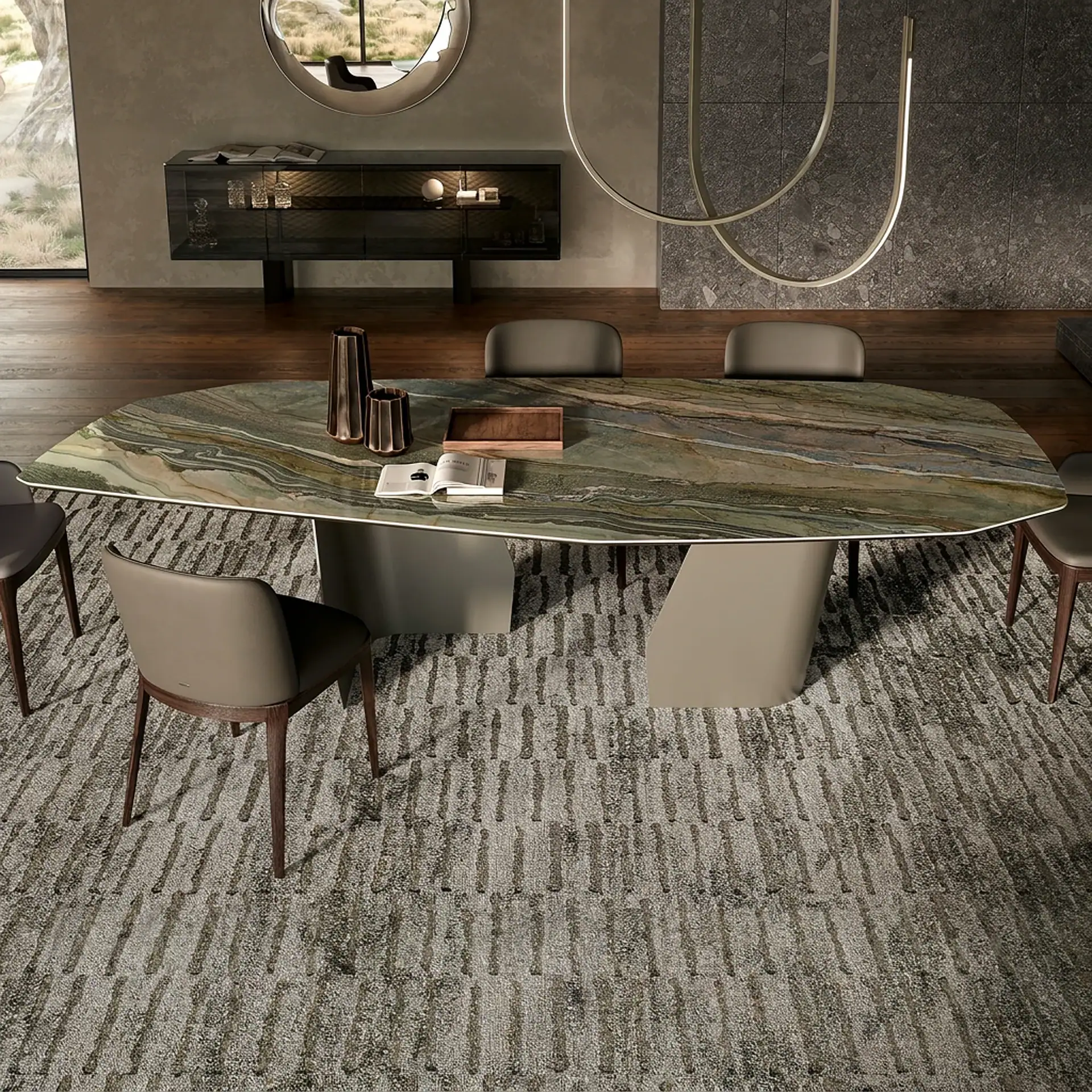 A modern dining room with a large oval marble-top table, six upholstered chairs, a textured rug, a dark sideboard, a circular mirror, and a minimalist chandelier.