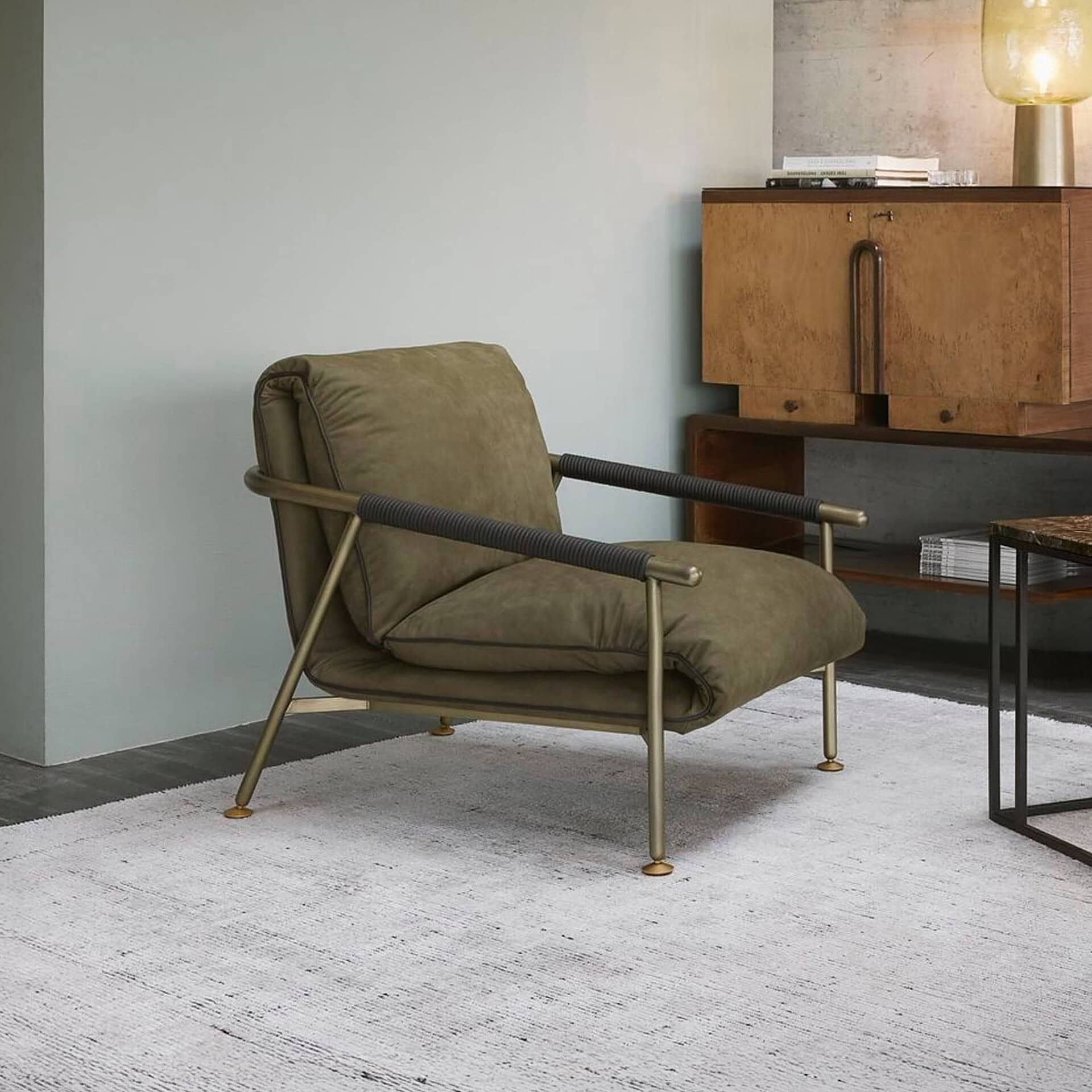 Modern olive green lounge chair with metal frame and plush cushion, stylishly placed in contemporary living room decor.