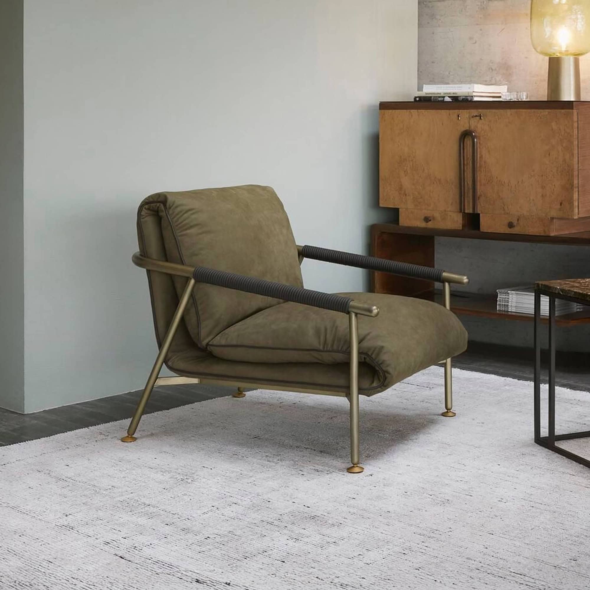 Modern olive green lounge chair with metal frame and plush cushion, stylishly placed in contemporary living room decor.