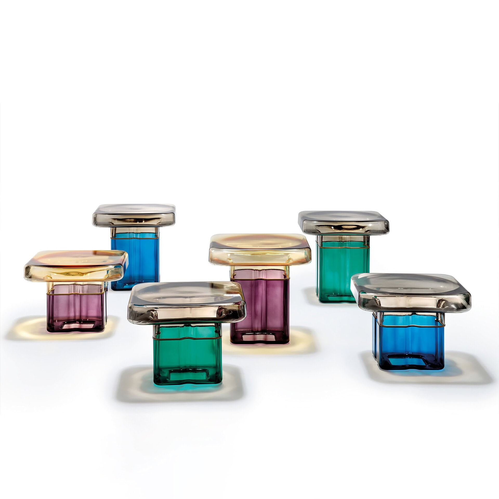 Six modern glass objects with rectangular colorful bases in blue, green, and purple, topped with rounded square smoky reflective caps, arranged on a white background.