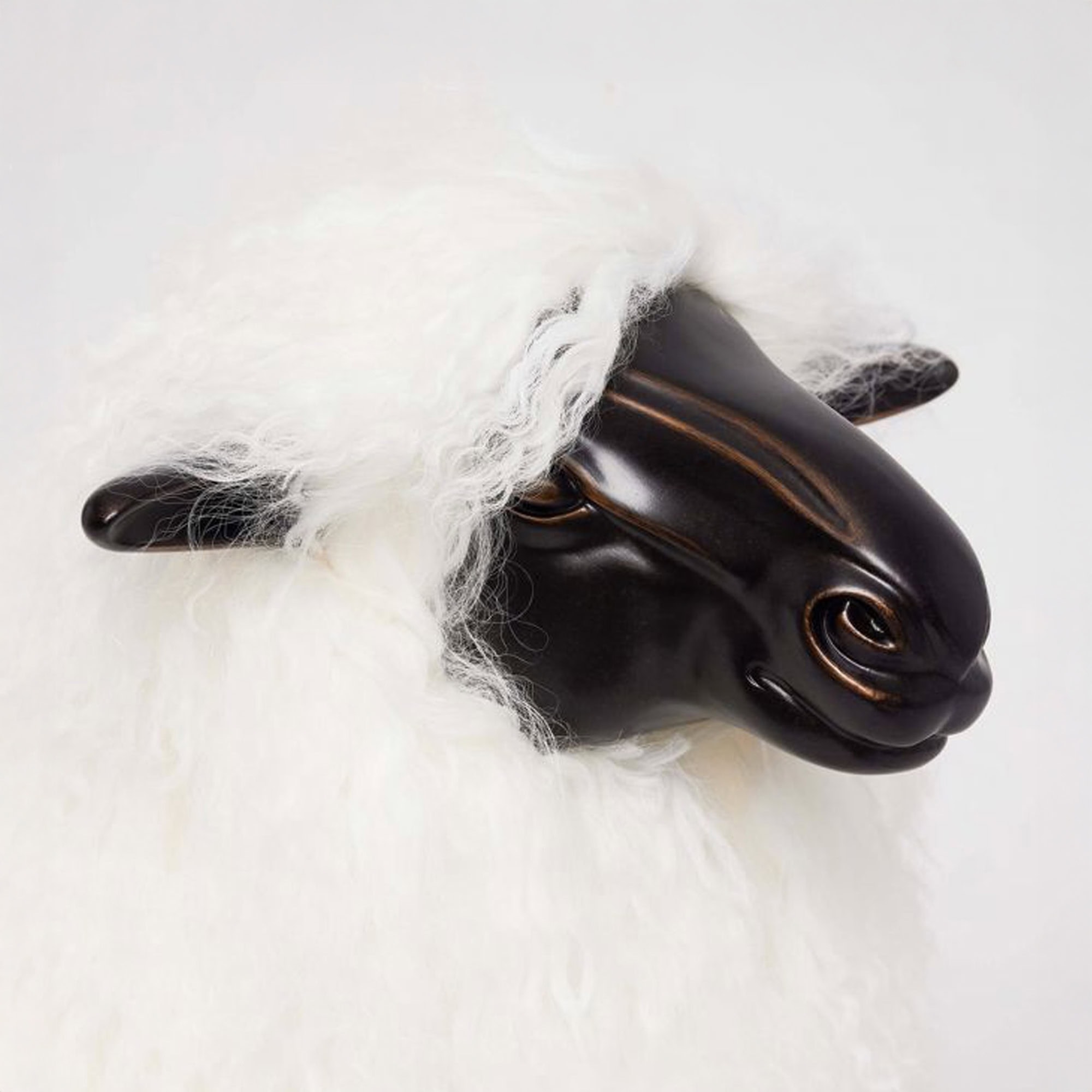 Close-up of sculpted bronze face on the Lucie Baby Sheep Statue with ivory sheepskin upholstery.