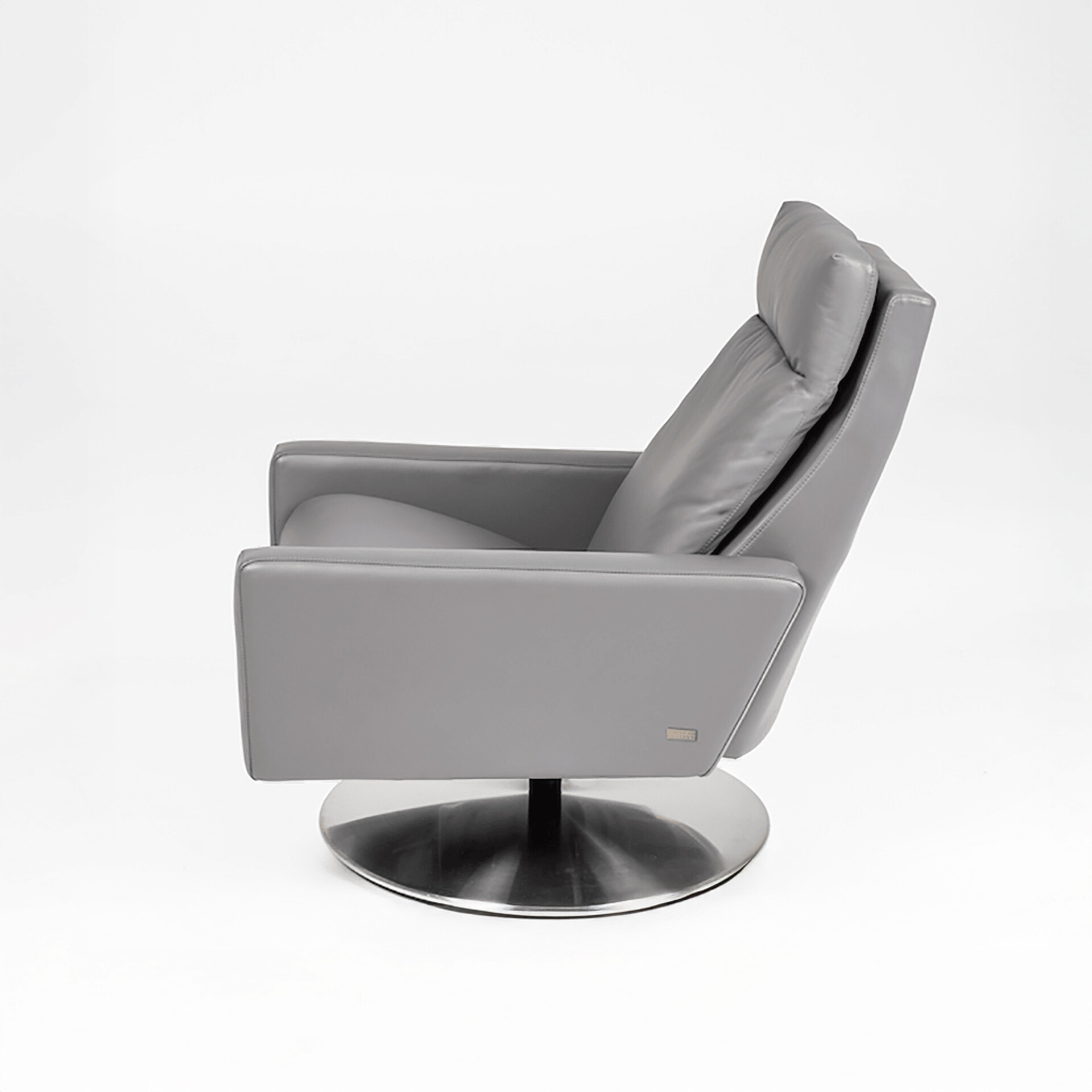 Side view of a modern light grey leather armchair with a plush headrest and a polished chrome circular swivel base, set against a white background.