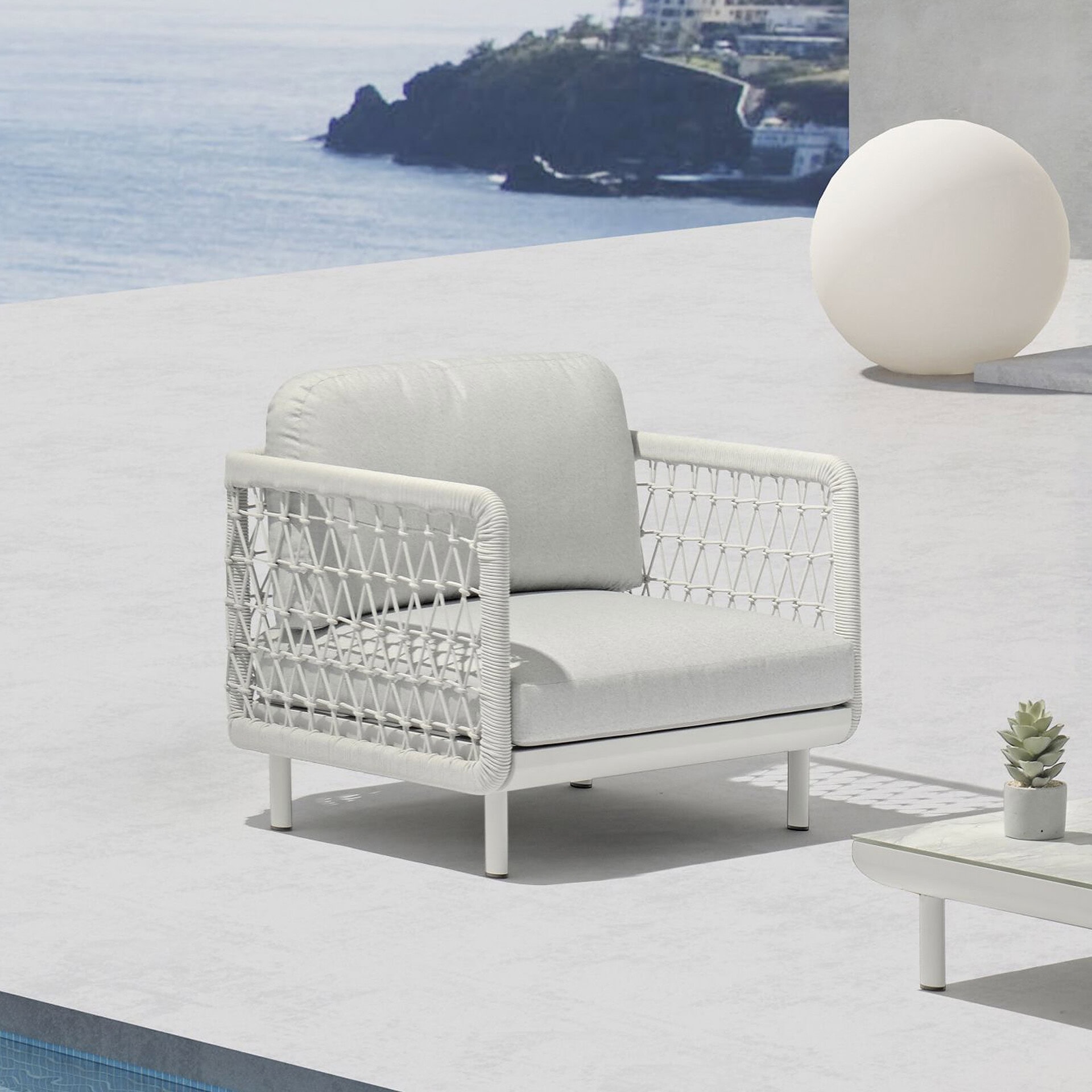 Outdoor white armchair with woven sides, perfect for coastal patio or poolside relaxation.