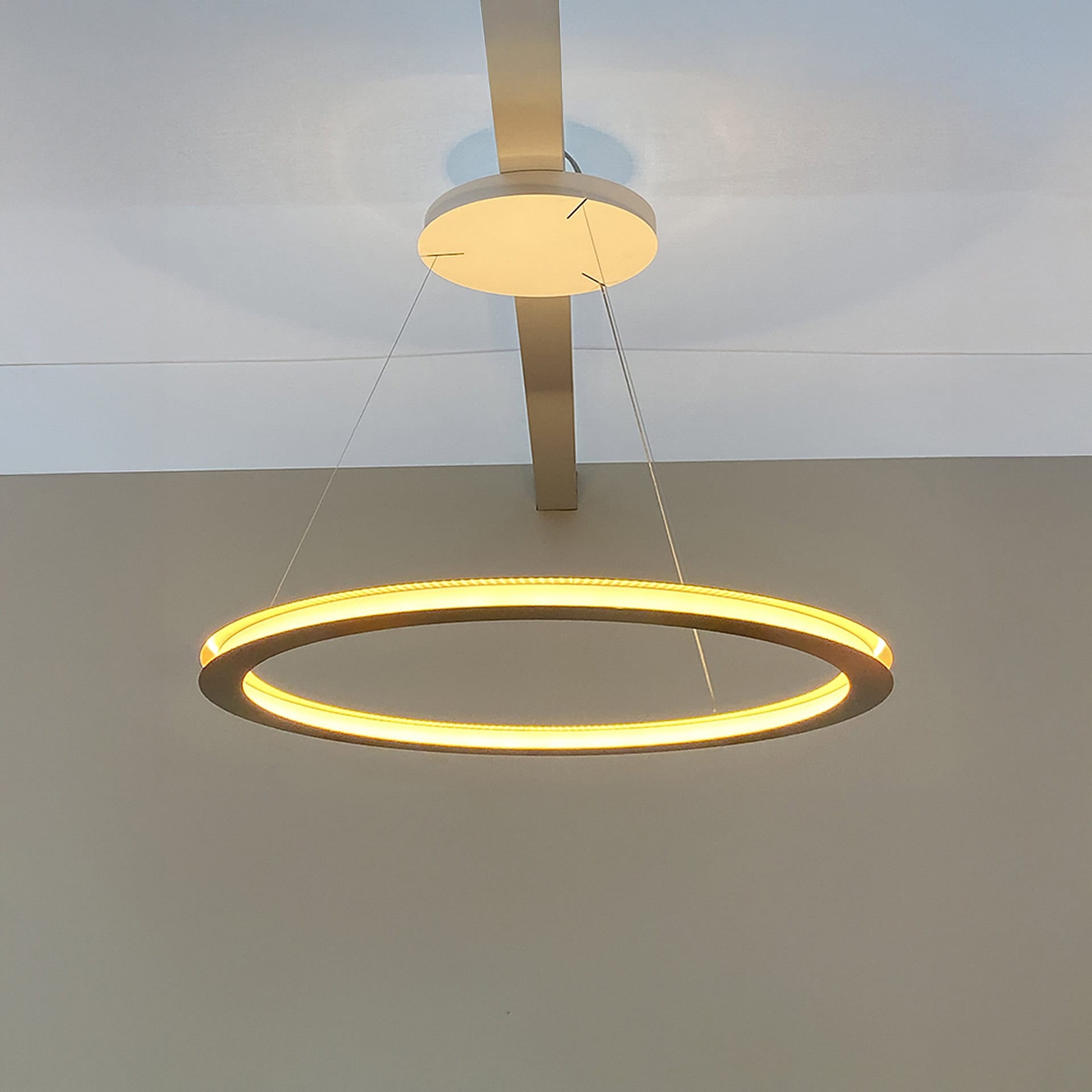 Contemporary LED ring pendant light hanging from ceiling.