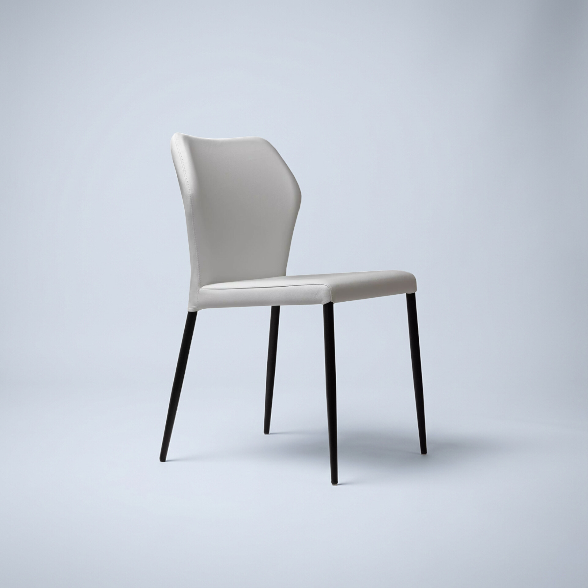 A modern dining chair with a light grey upholstered seat and curved backrest, supported by four slender black tapered legs, against a light grey background.