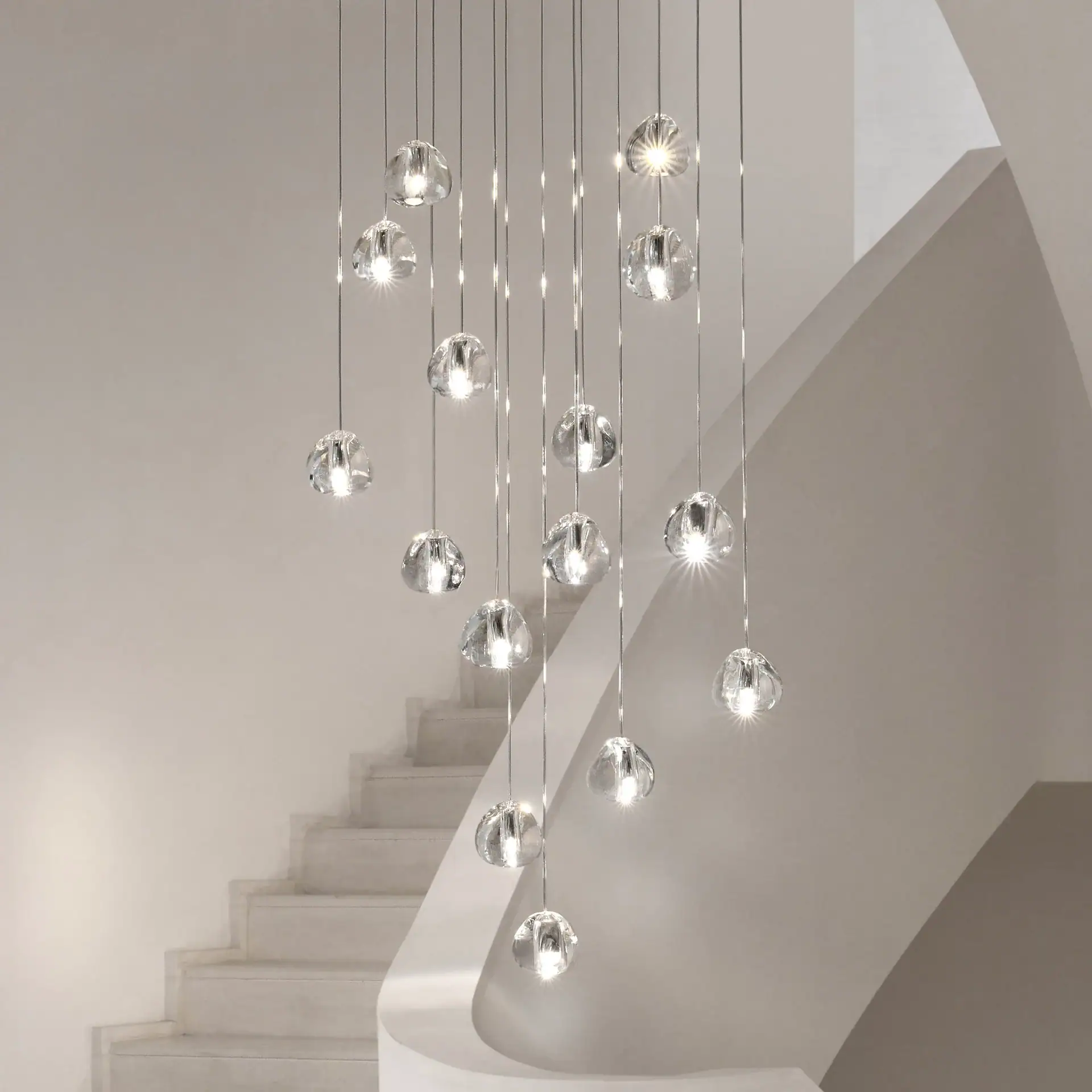Elegant glass pendant chandelier hanging above staircase in contemporary interior.