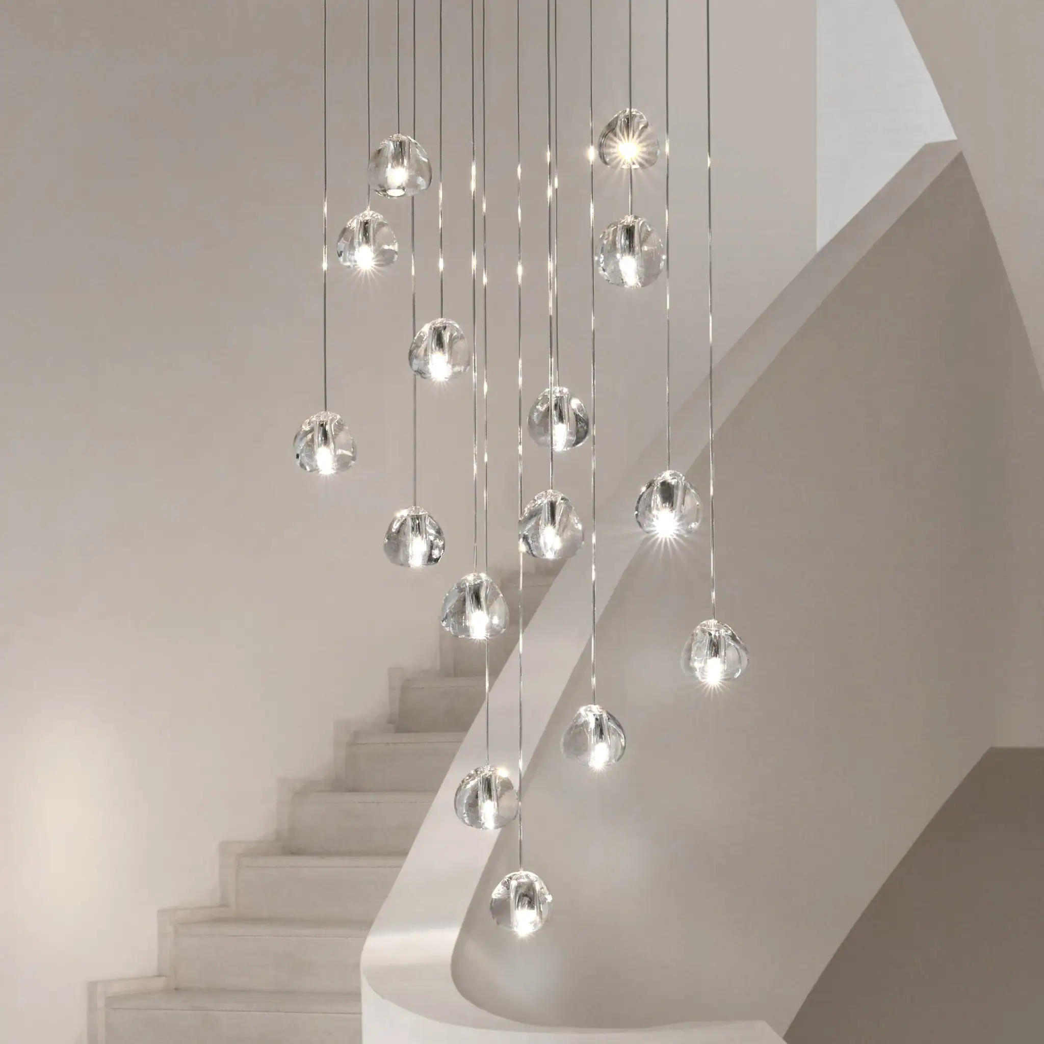Elegant glass pendant chandelier hanging above staircase in contemporary interior.