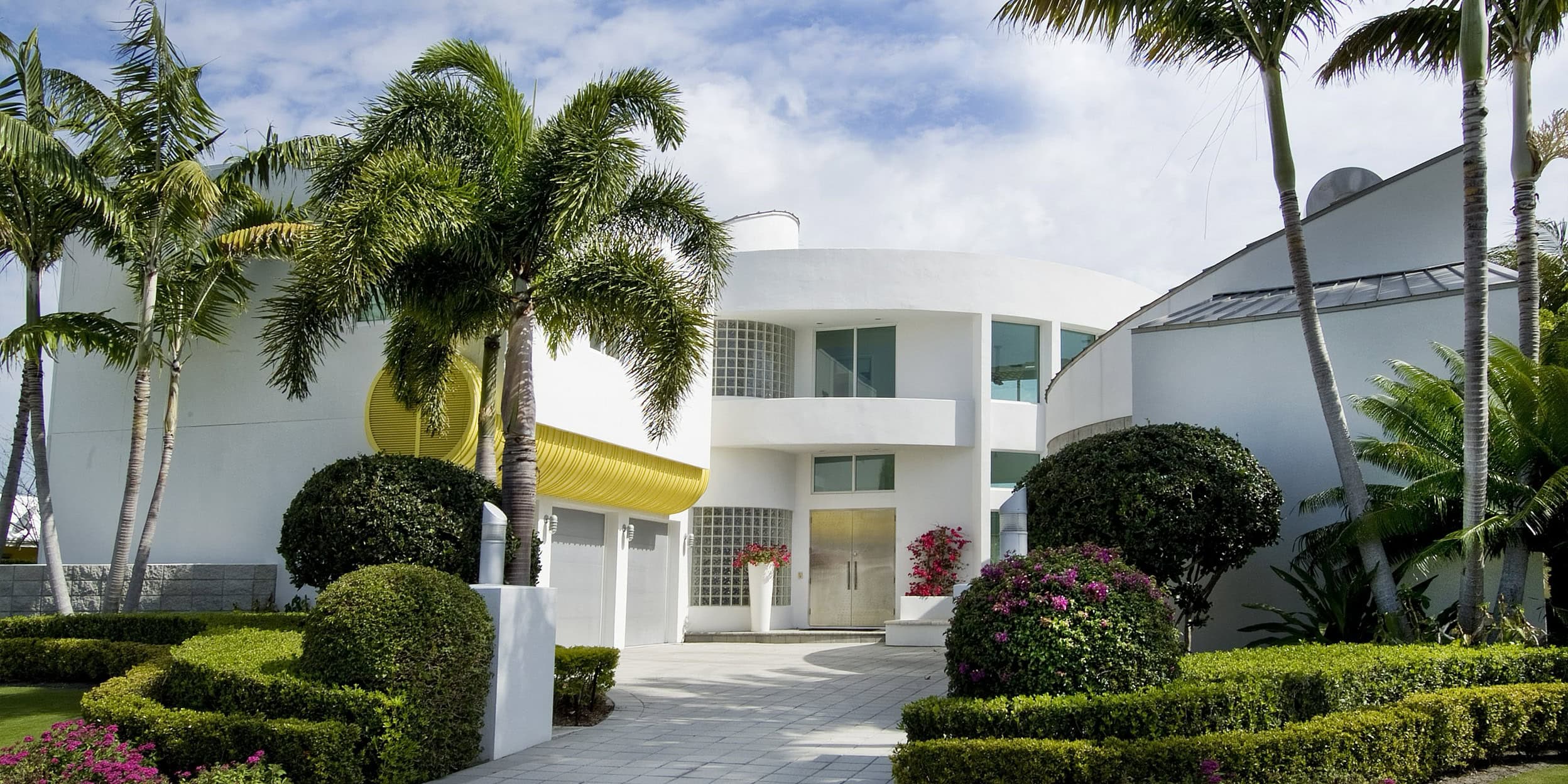a white house with palm trees and bushes