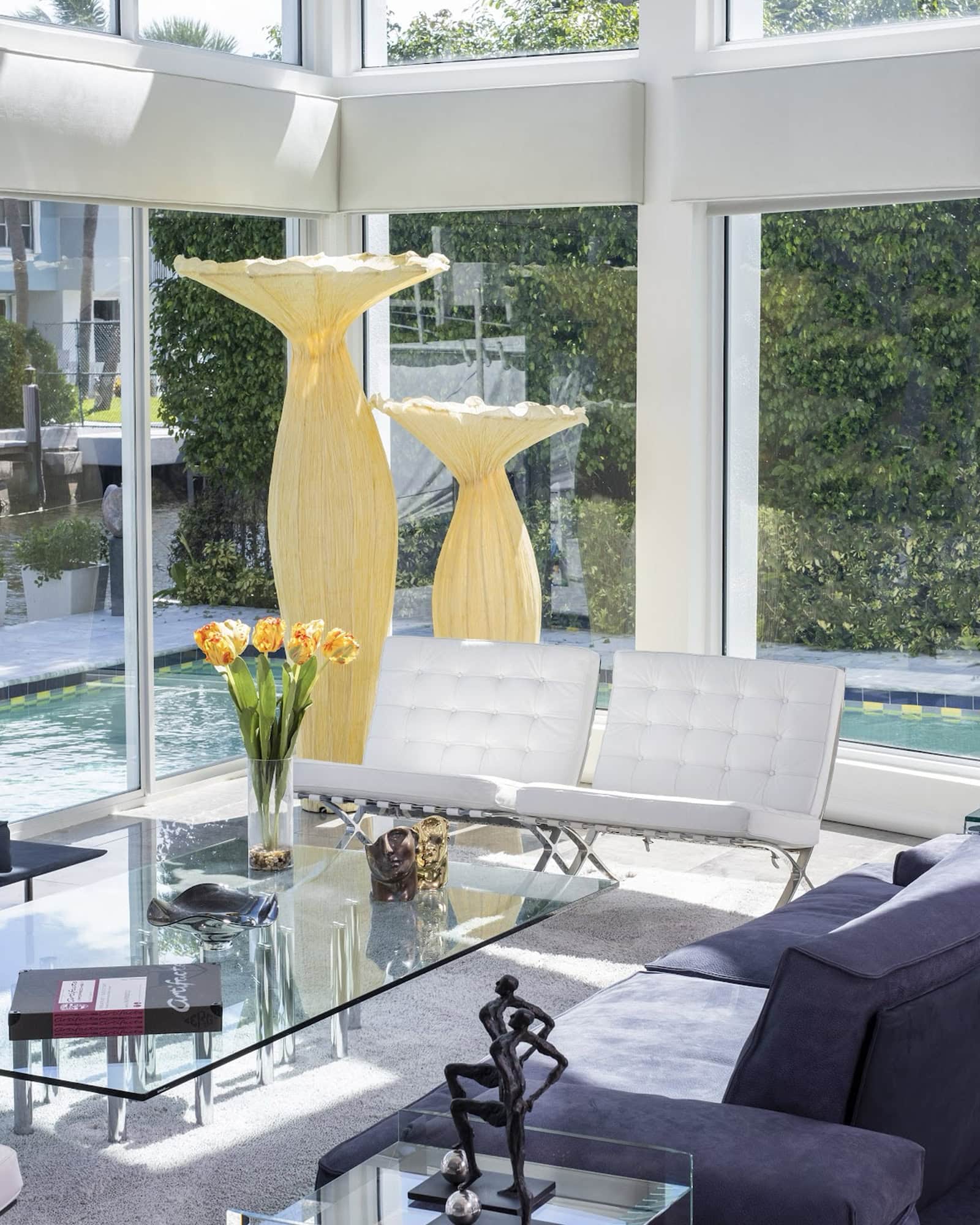 A living room with large windows and a glass table.