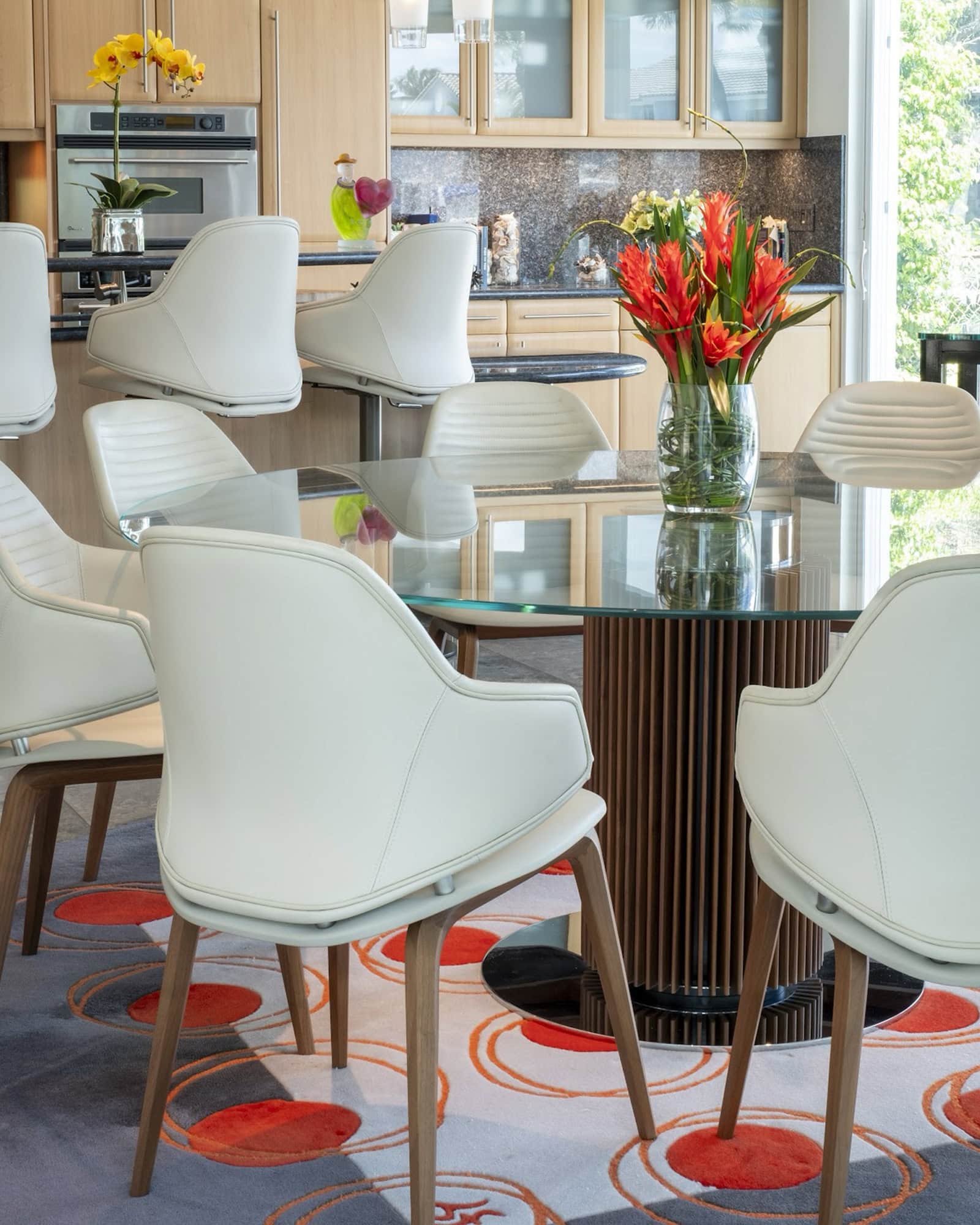 a dining table with chairs and a vase of flowers