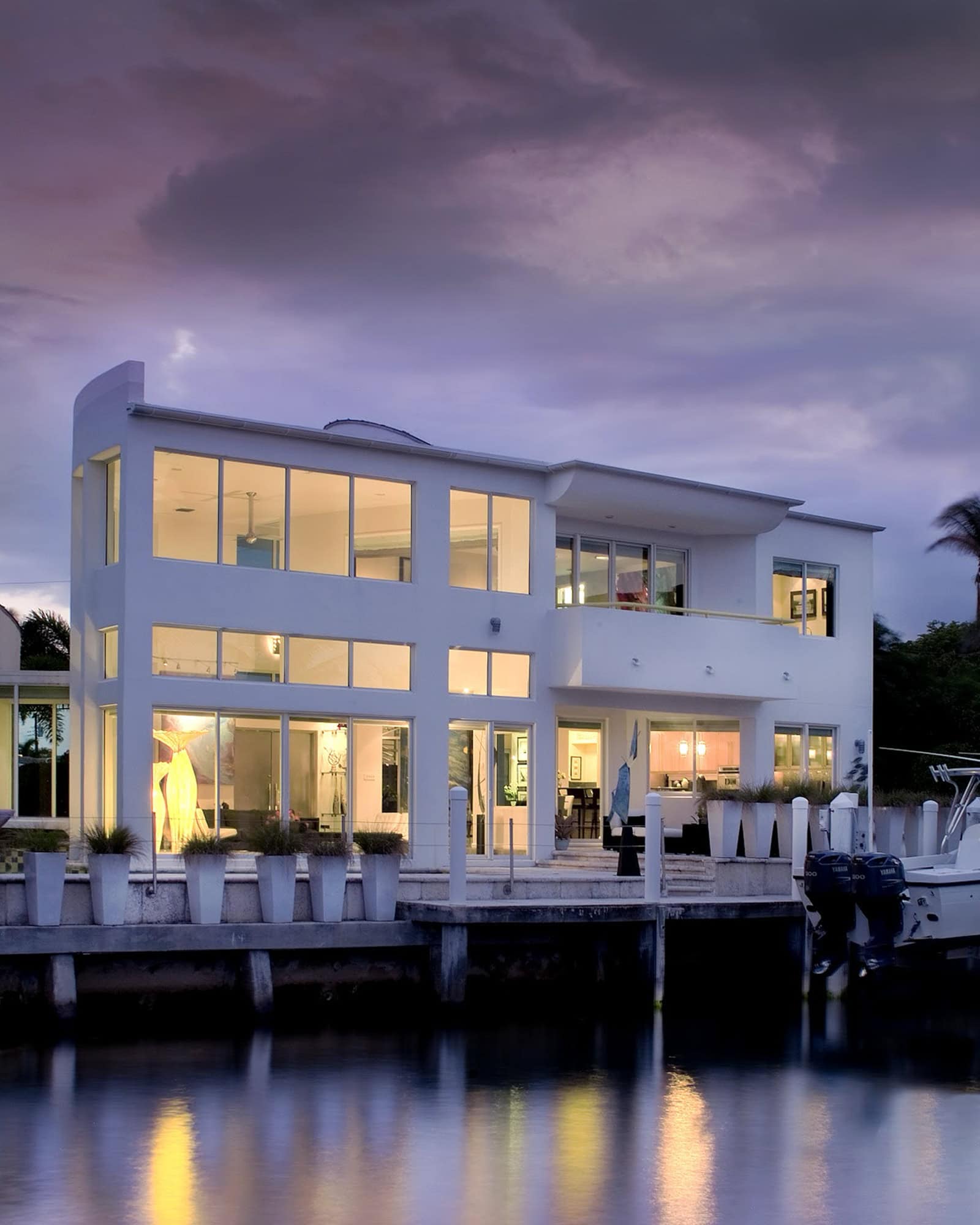 A large white house with a boat dock at dusk.