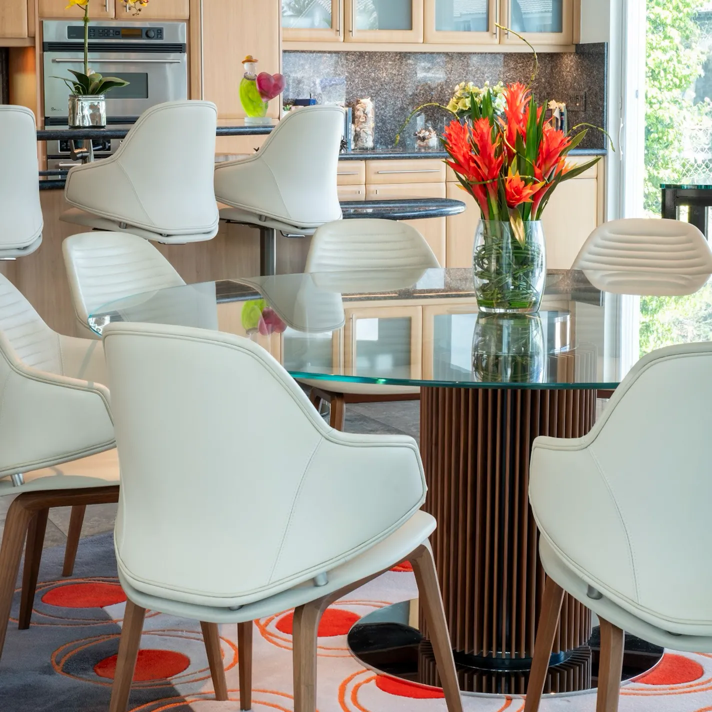a dining table with chairs and a vase of flowers
