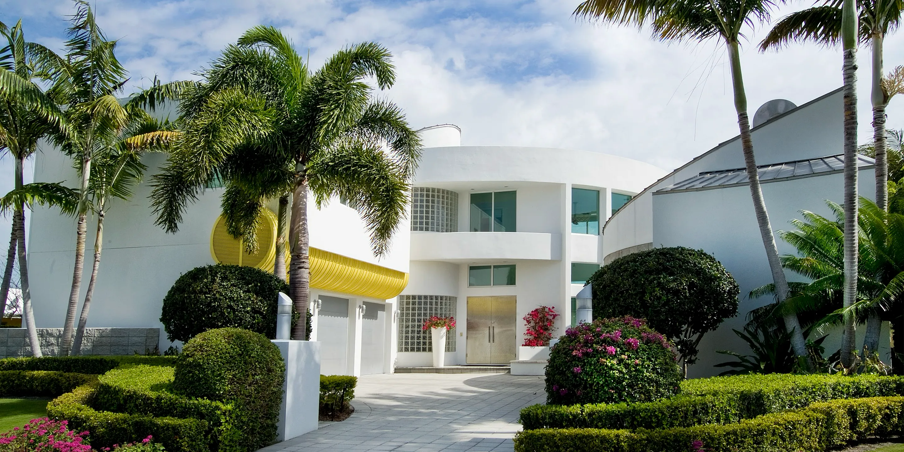 a white house with palm trees and bushes