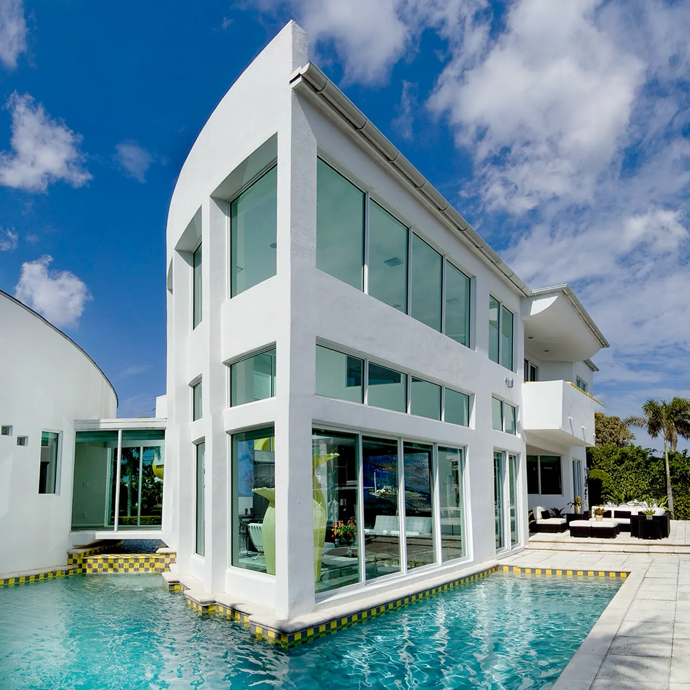 A living room with large windows and a glass table.