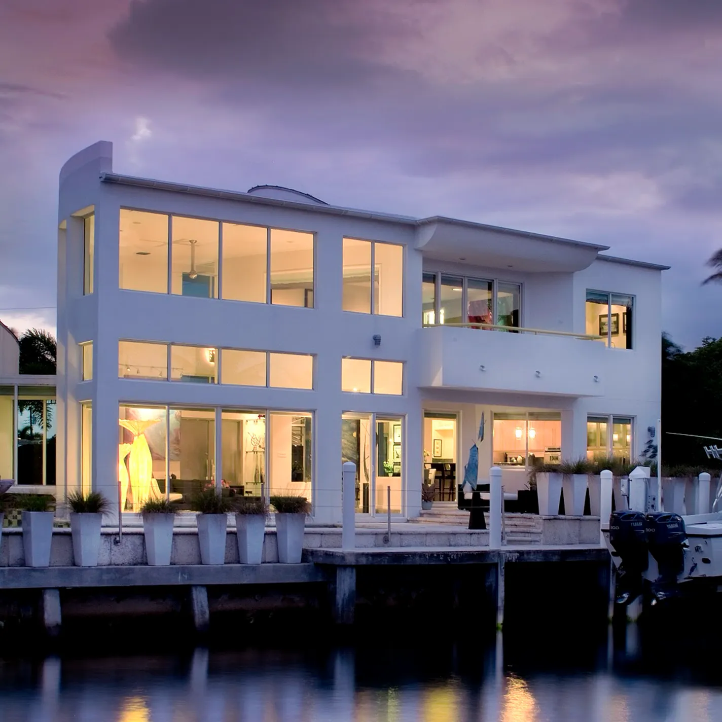 A large white house with a boat dock at dusk.
