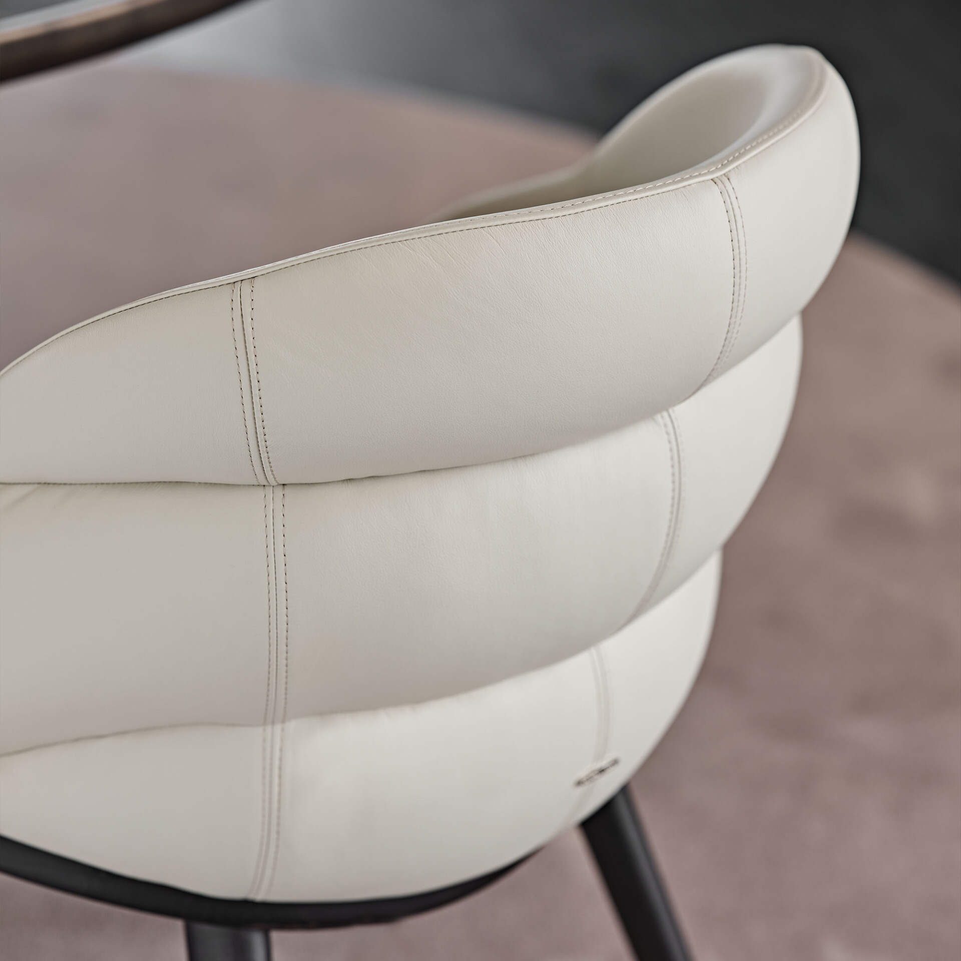 Close-up of an ivory leather chair backrest with three plush, segmented cushions and vertical stitching, showcasing a modern and luxurious design.