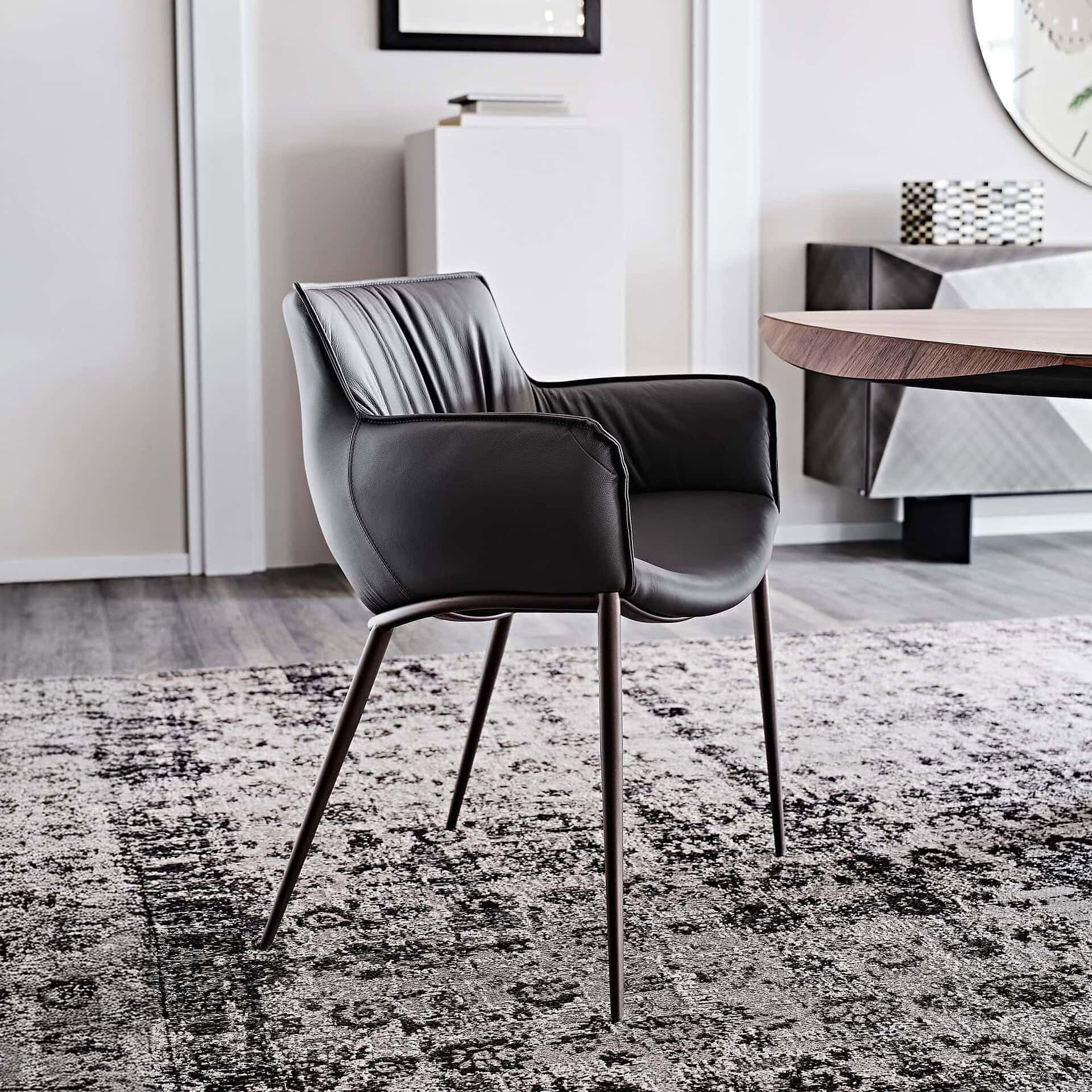 Rhonda Dining Chair in soft taupe leather with slim metal legs, shown in a modern dining room.
