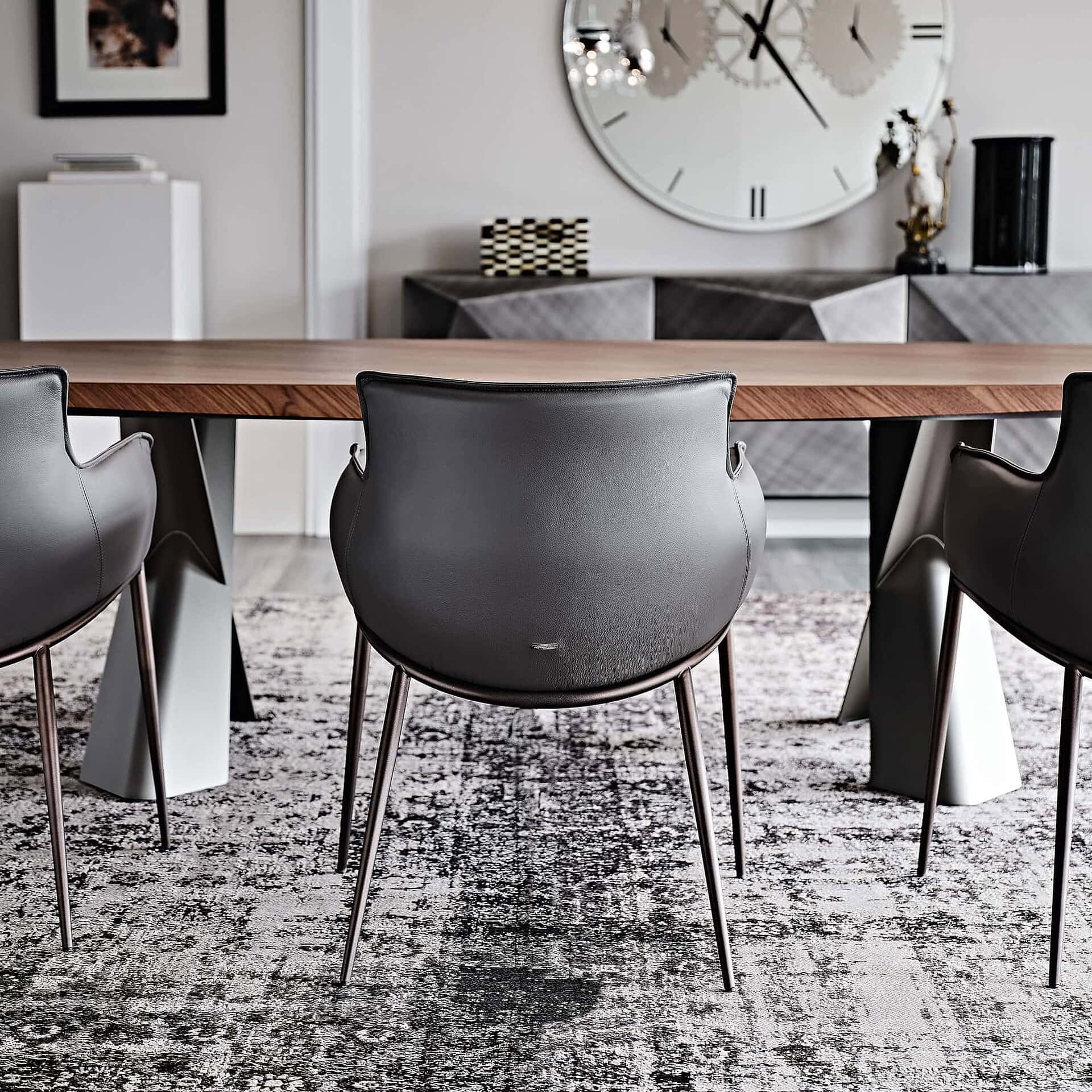 Set of Rhonda Dining Chairs in dark leather arranged around a contemporary dining table.