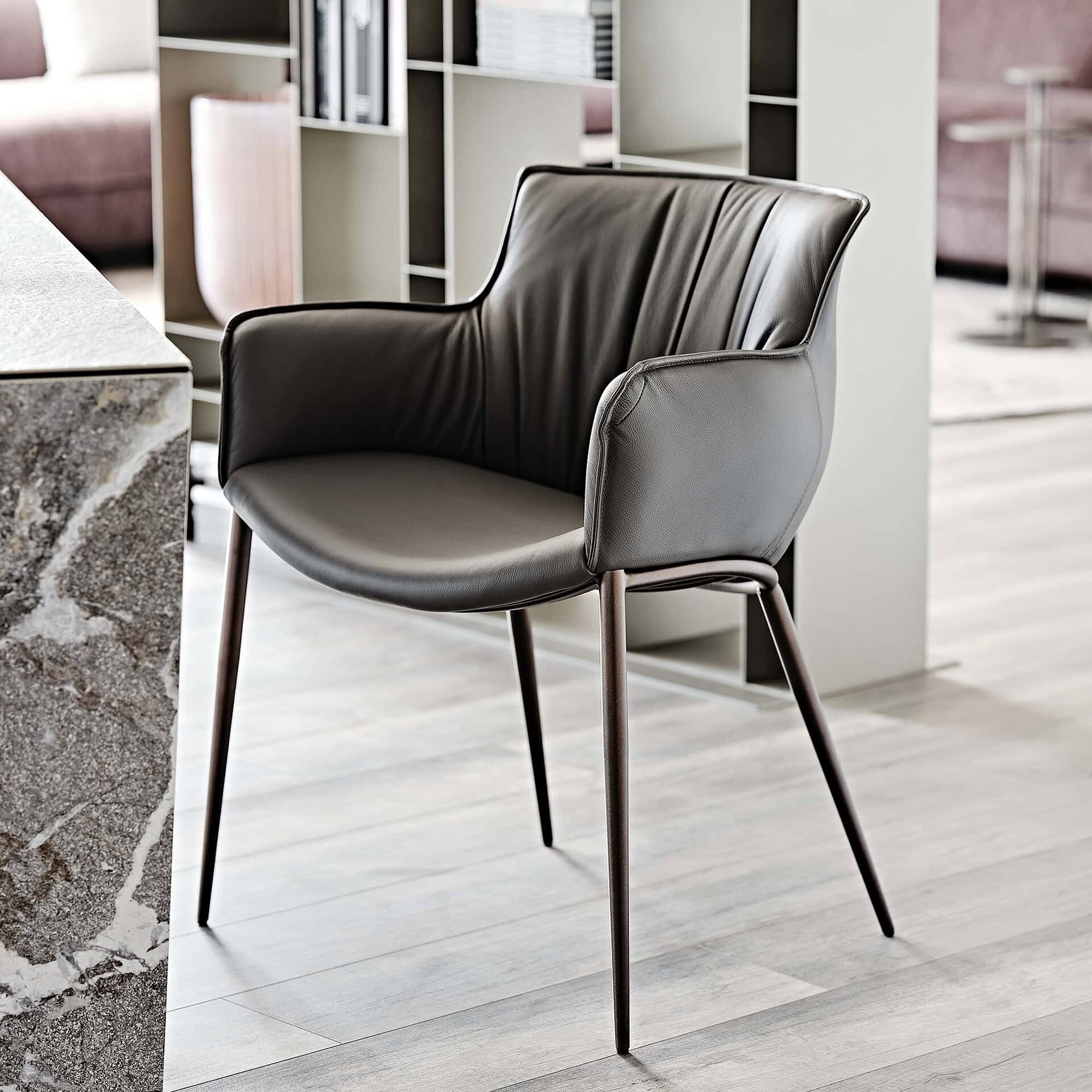 Close-up of the Rhonda Dining Chair in charcoal leather with stitched detailing and slim legs.