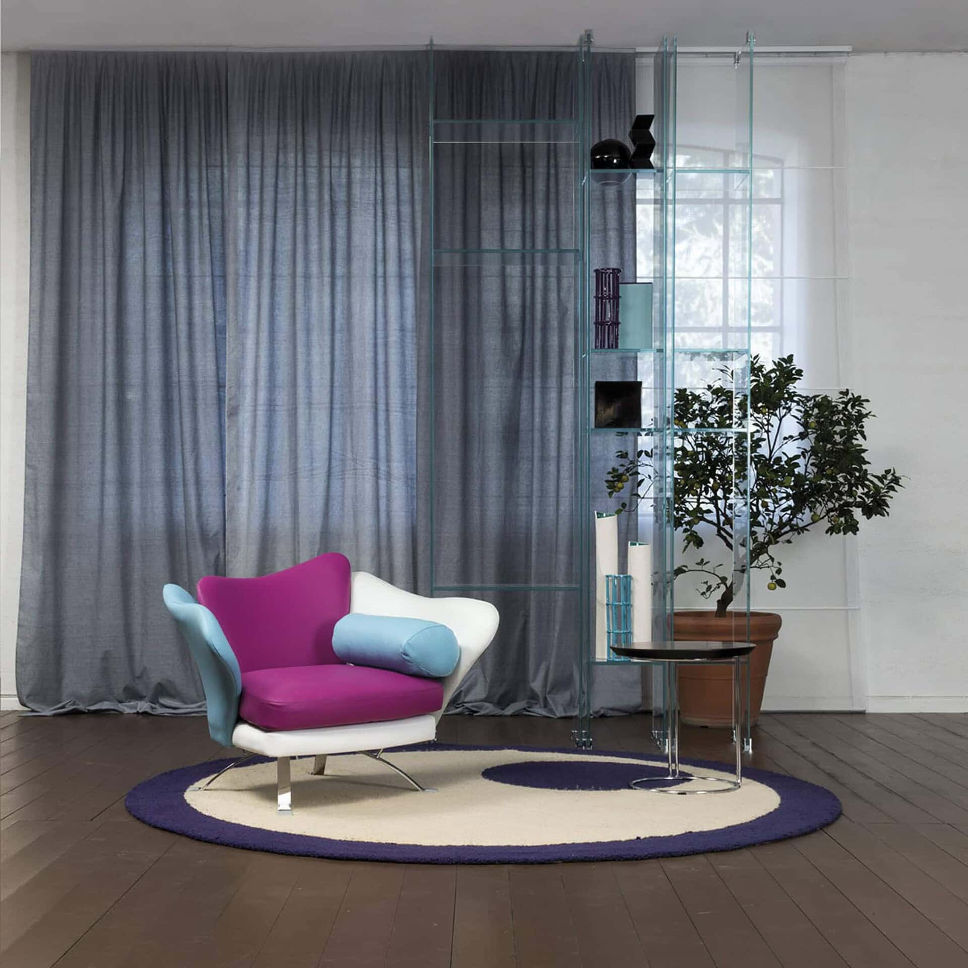 Flower Armchair in pink and white fabric on a round rug, styled with sheer blue curtains and potted plant