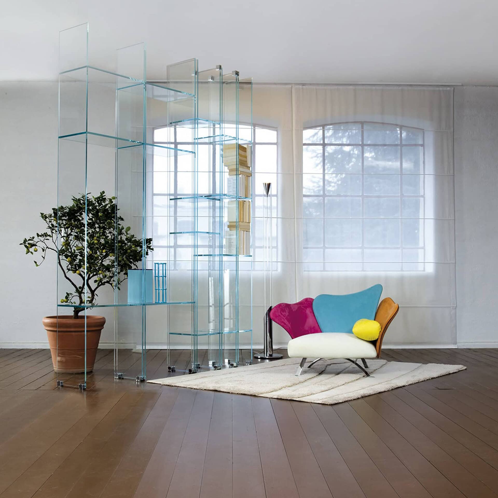 Flower Armchair in bright pink and yellow fabric displayed in a contemporary room with glass shelving and natural light