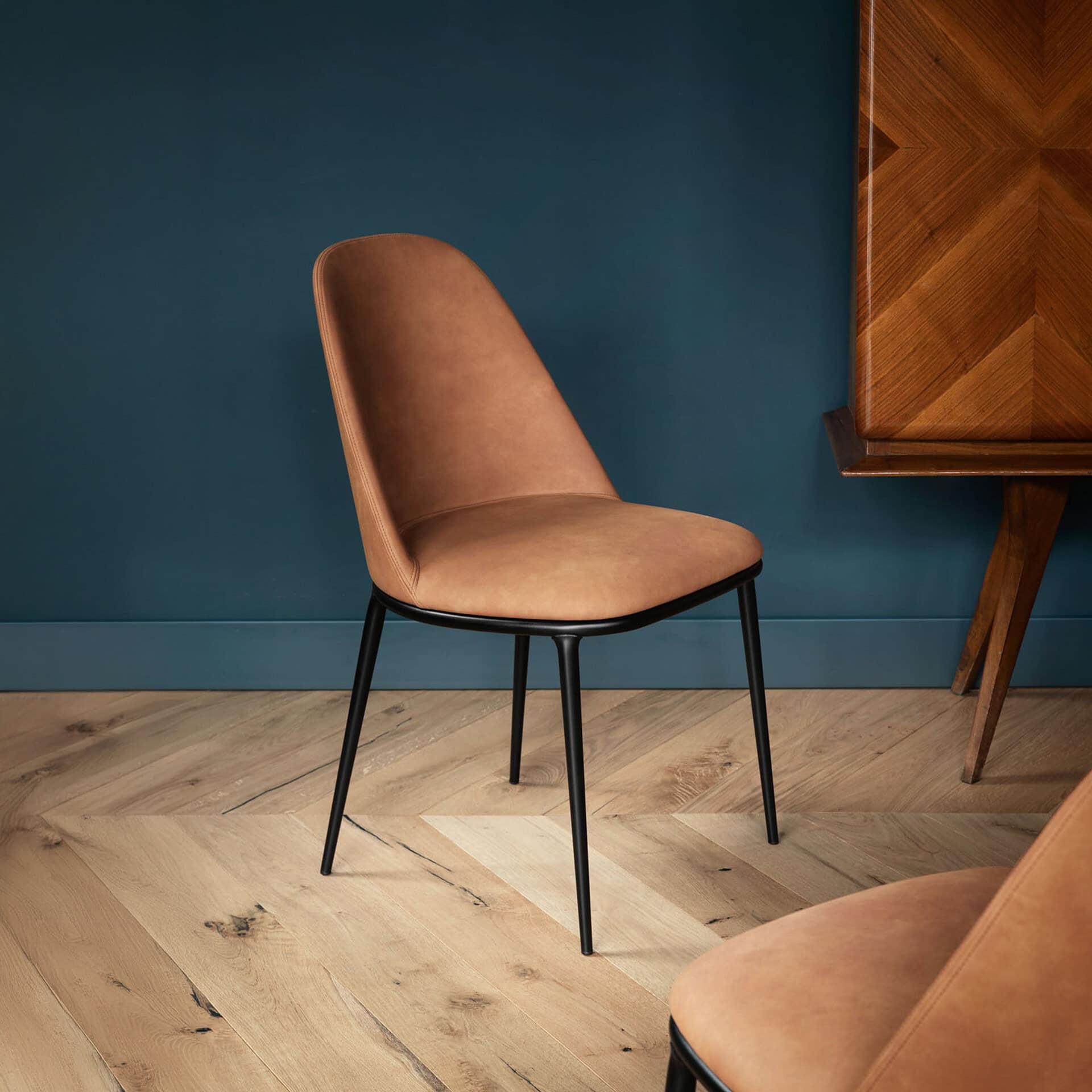 Elegant upholstered dining chair with black metal legs in stylish interior.