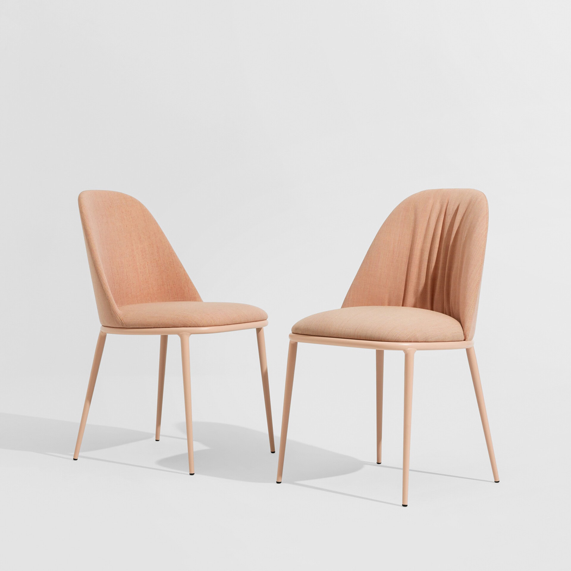 Elegant peach upholstered dining chairs with sleek wooden legs for contemporary interiors.
