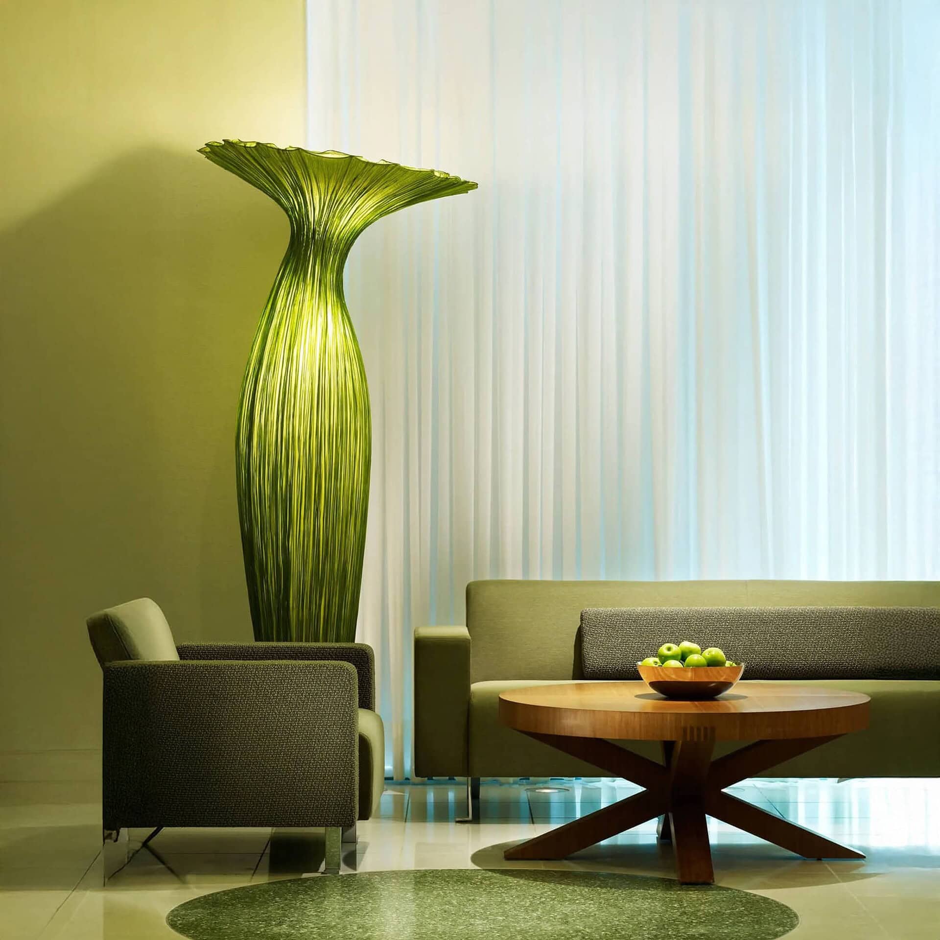 Elegant living room with modern green accent pieces and stylish furniture from Sklar Furnishings.