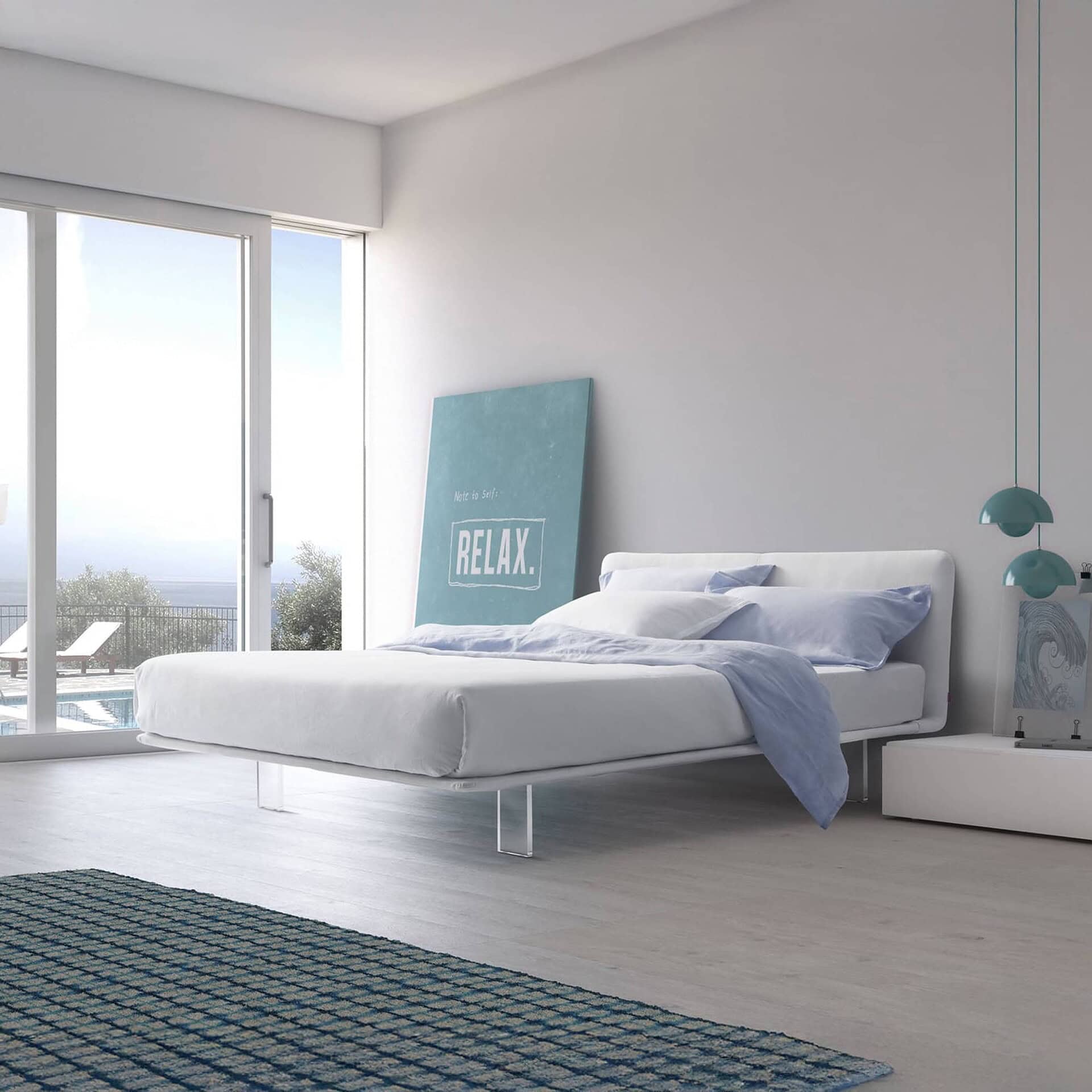 A modern bedroom with a white bed, light blue bedding, and large glass doors opening to an ocean view with a pool. A 'RELAX' poster leans against the wall, and teal pendant lights hang above a white bedside table.