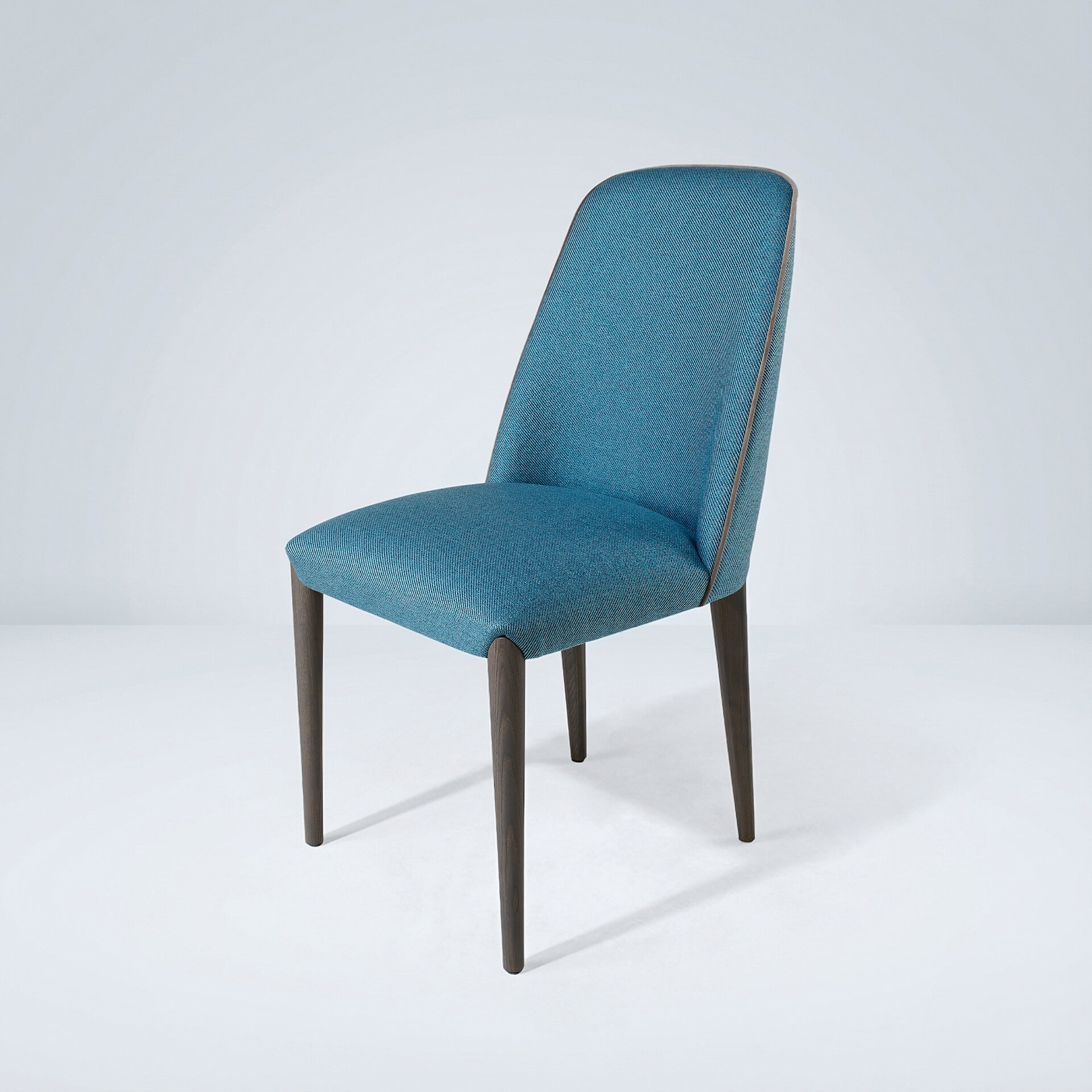A modern teal upholstered dining chair with dark wooden legs and light brown piping, set against a light gray background.
