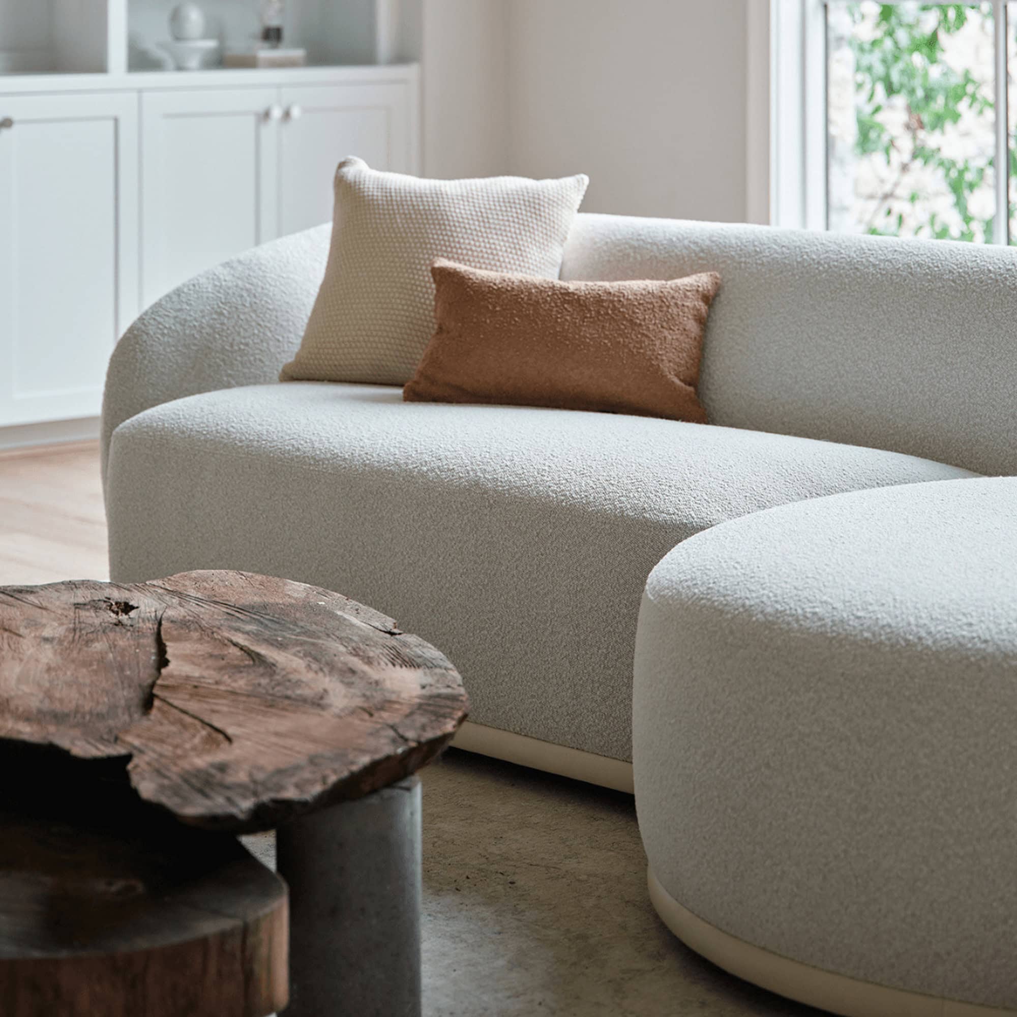 Athlea Sofa in a contemporary space paired with a round ottoman and wooden coffee table.