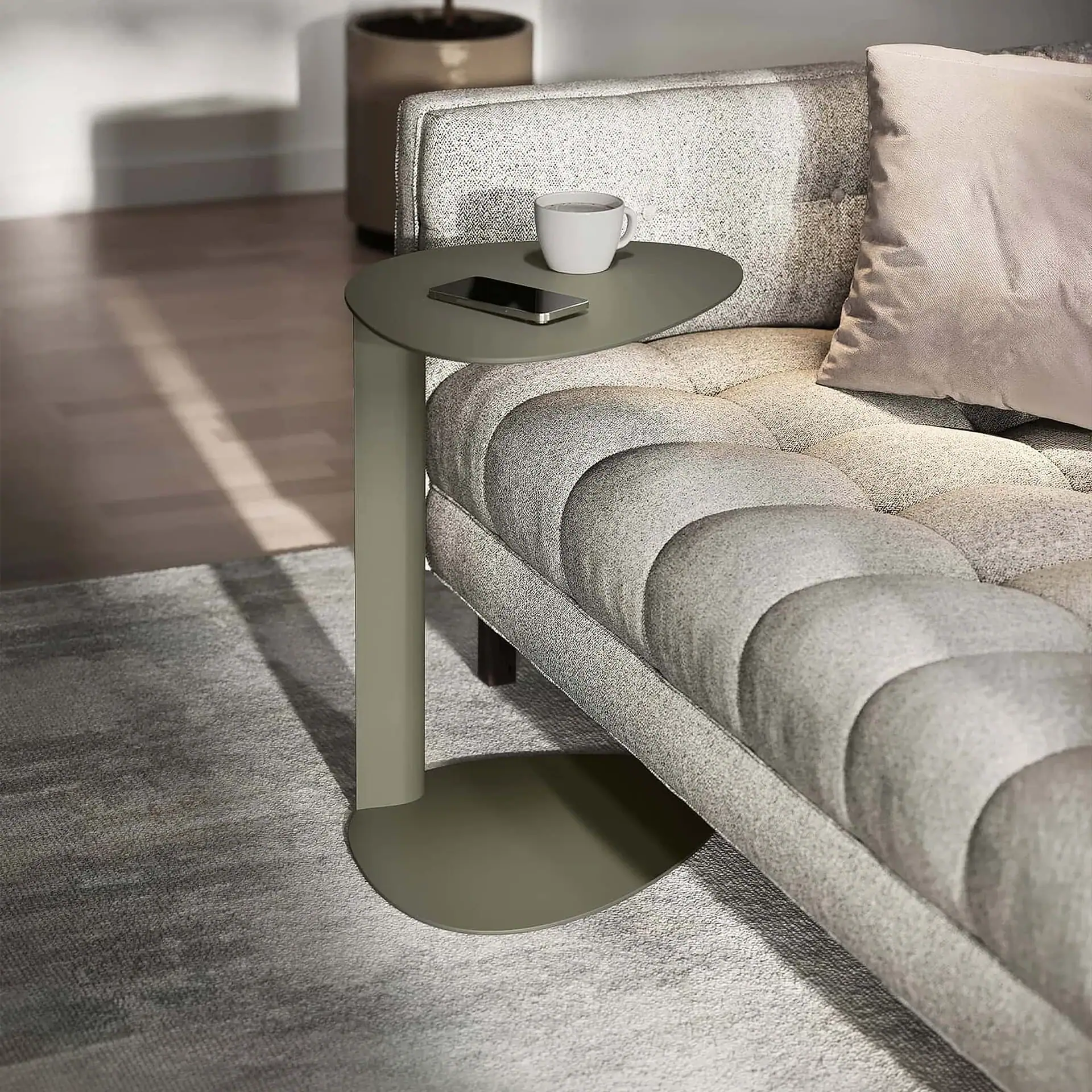 Modern side table attached to sofa with coffee mug and phone on top.