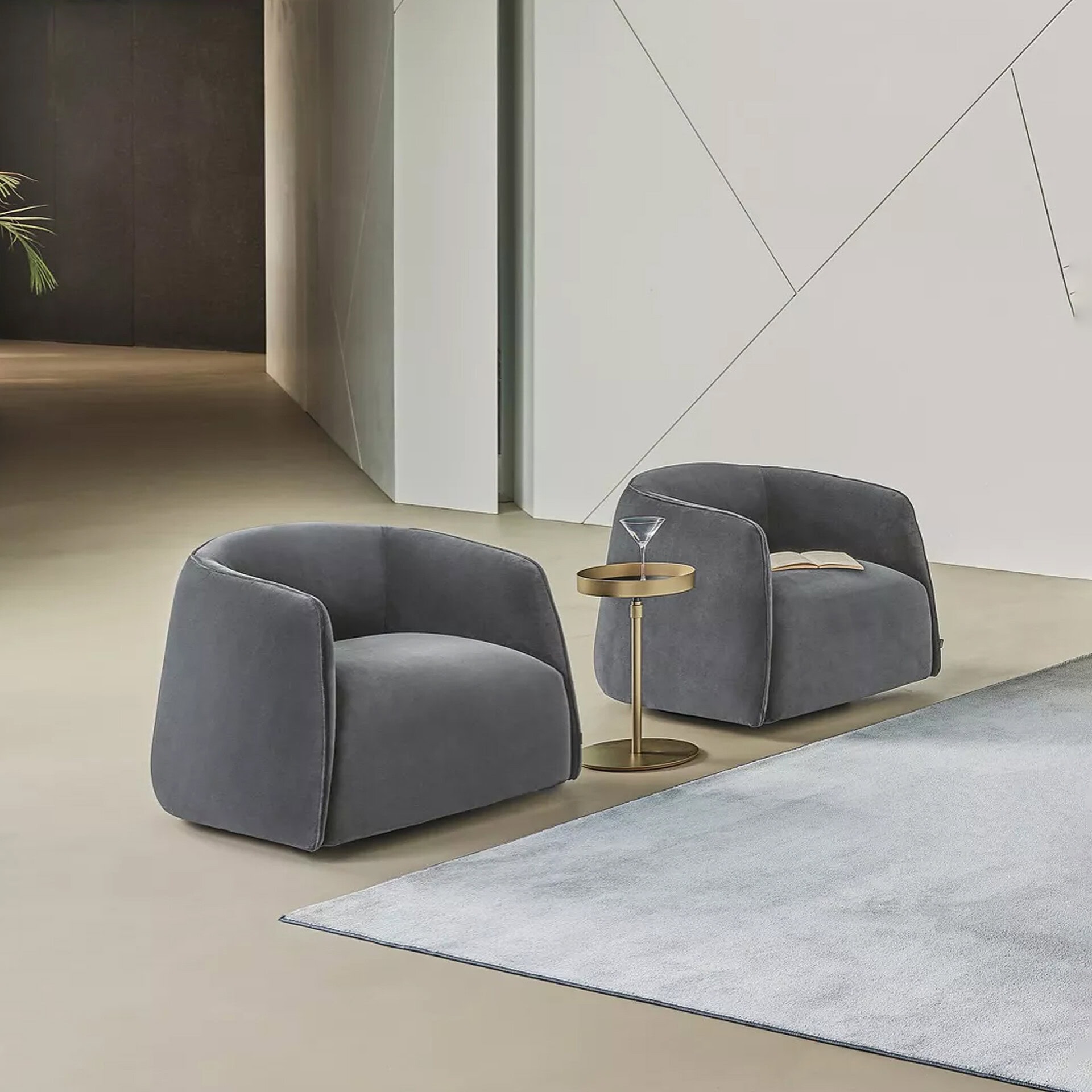 A pair of stylish gray armchairs with a small gold side table, ideal for modern and luxury interior settings.
