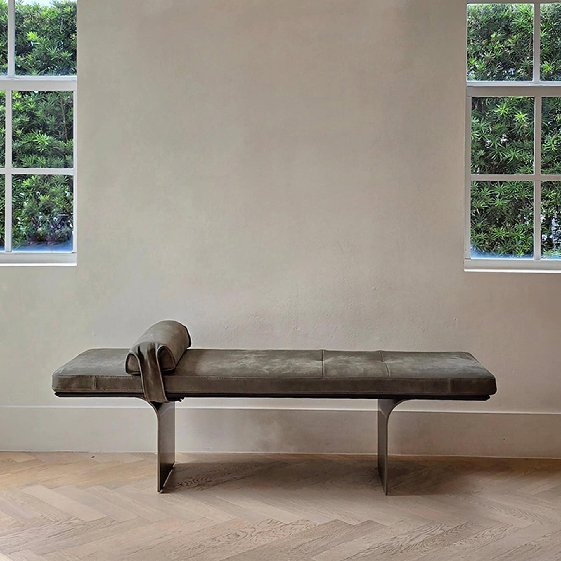 Minerva Leather Bench upholstered in neutral fabric against a textured wall with windows.