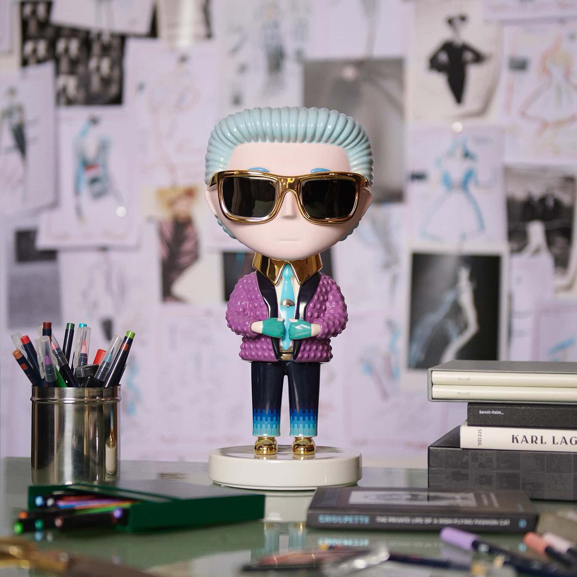 Karl Lagerfeld Pop Art Sculpture displayed on a desk with colorful pens, books, and a fashion mood board background.