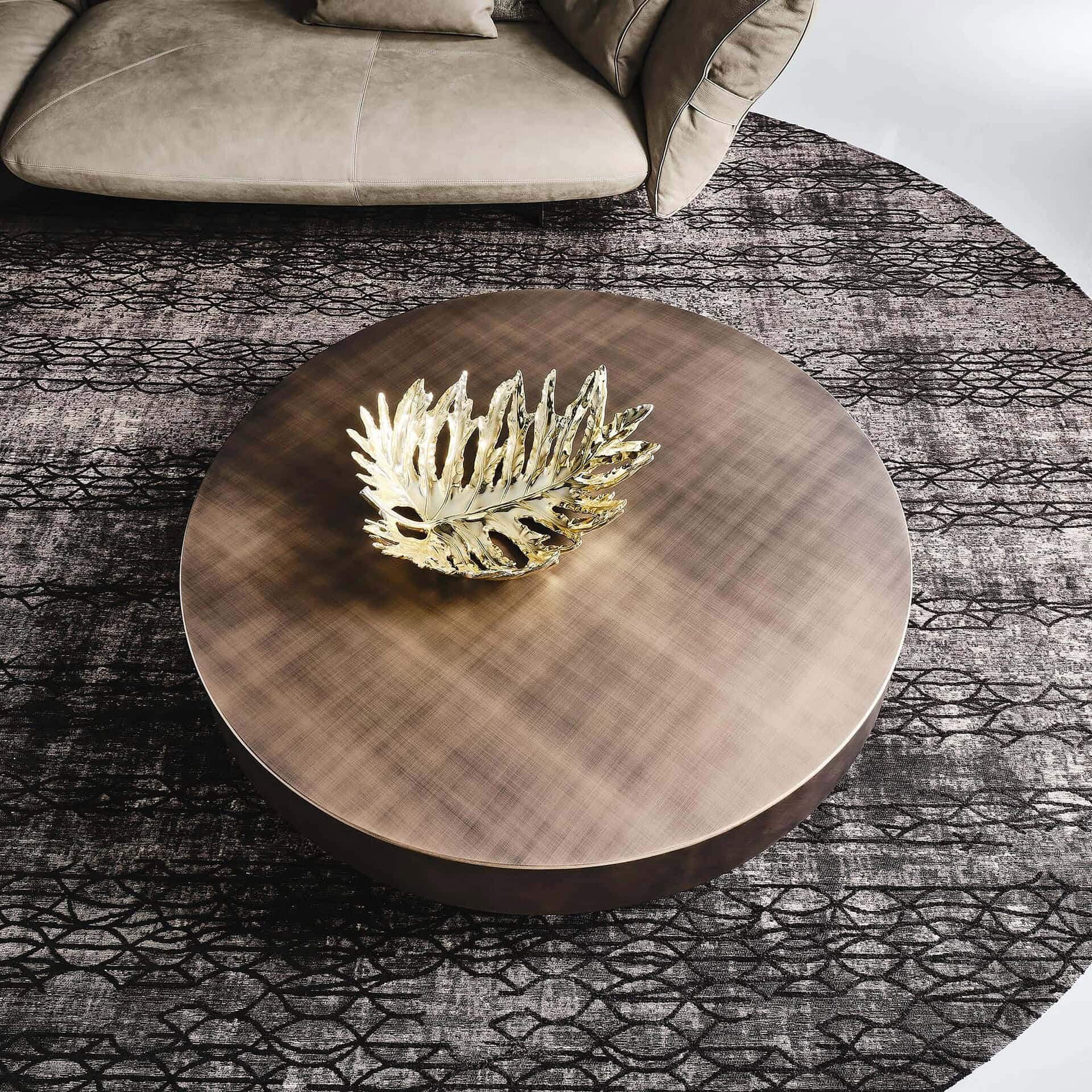 Arena Hand-Brushed Coffee Table in a round design with brushed bronze top set against a colorful modern backdrop.