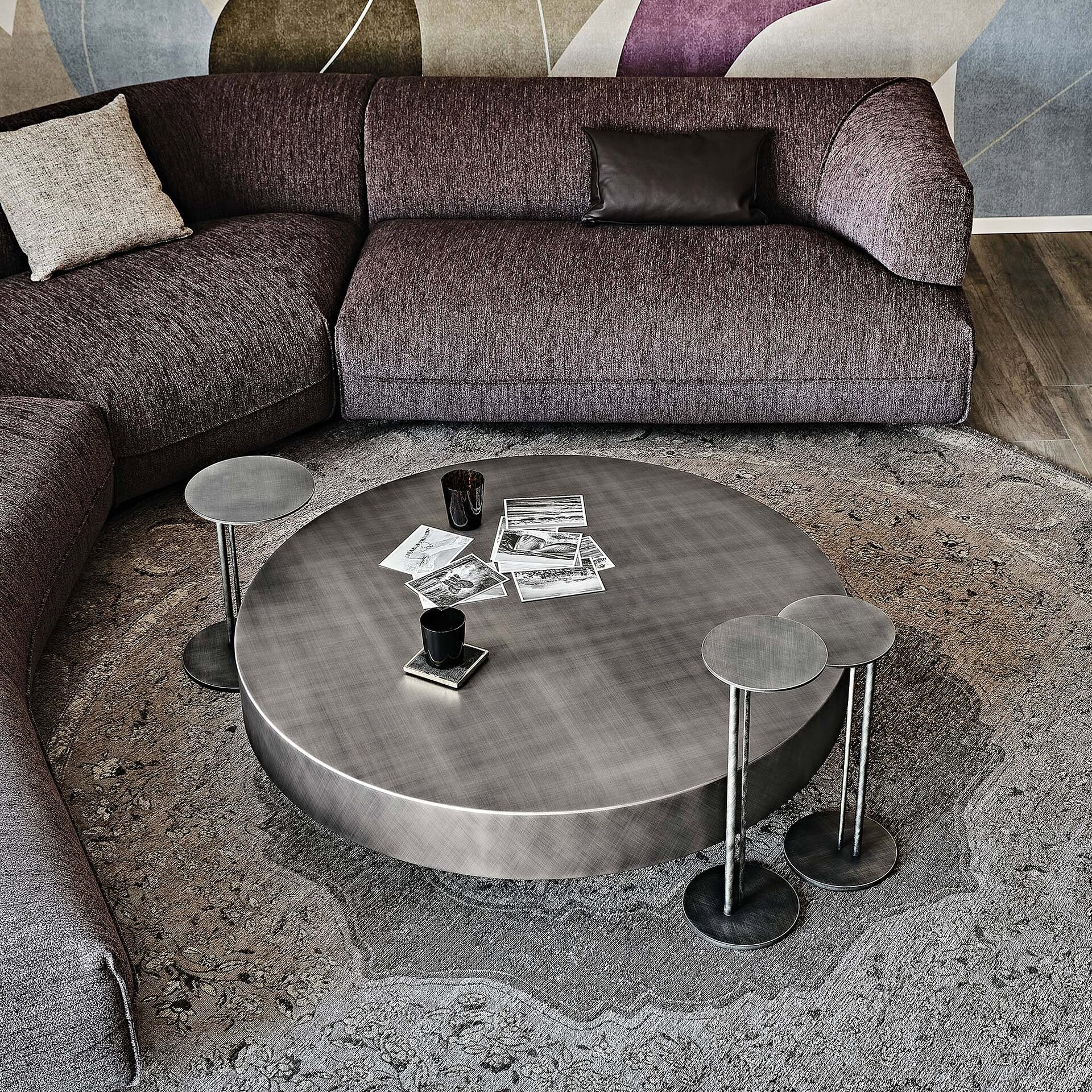 Arena Hand-Brushed Coffee Table with round glass beveled top and bronze base styled in a cozy living space.
