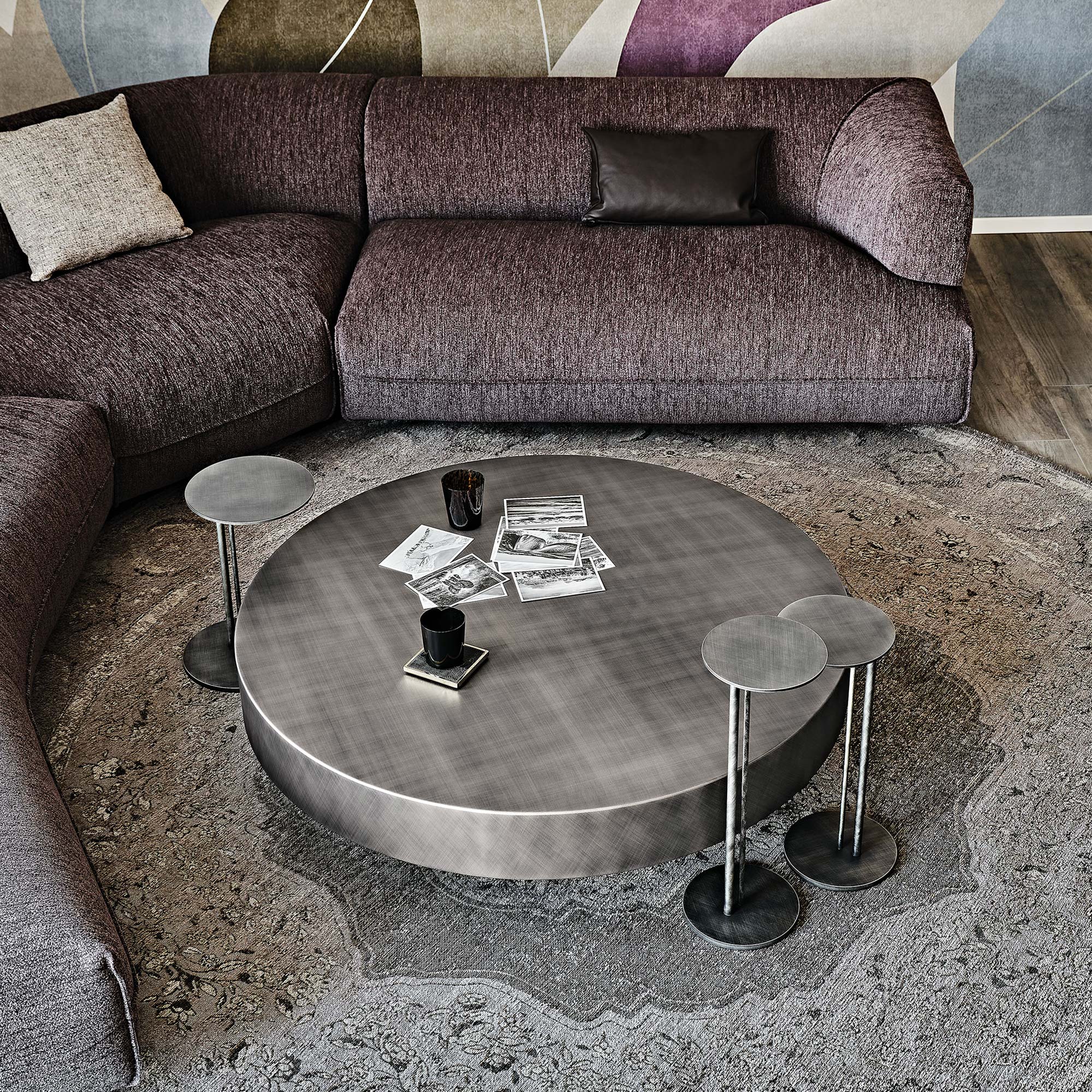 Arena Hand-Brushed Coffee Table with round glass beveled top and bronze base styled in a cozy living space.